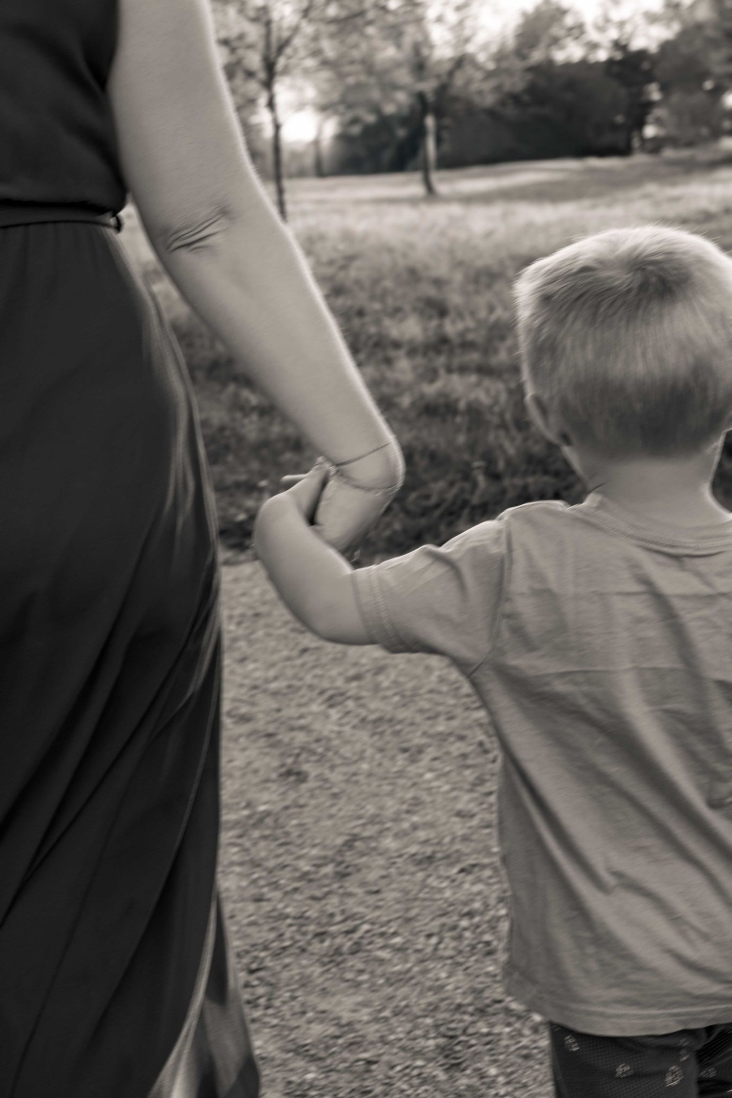 Black and white image of figures walking hand in hand on nature path.