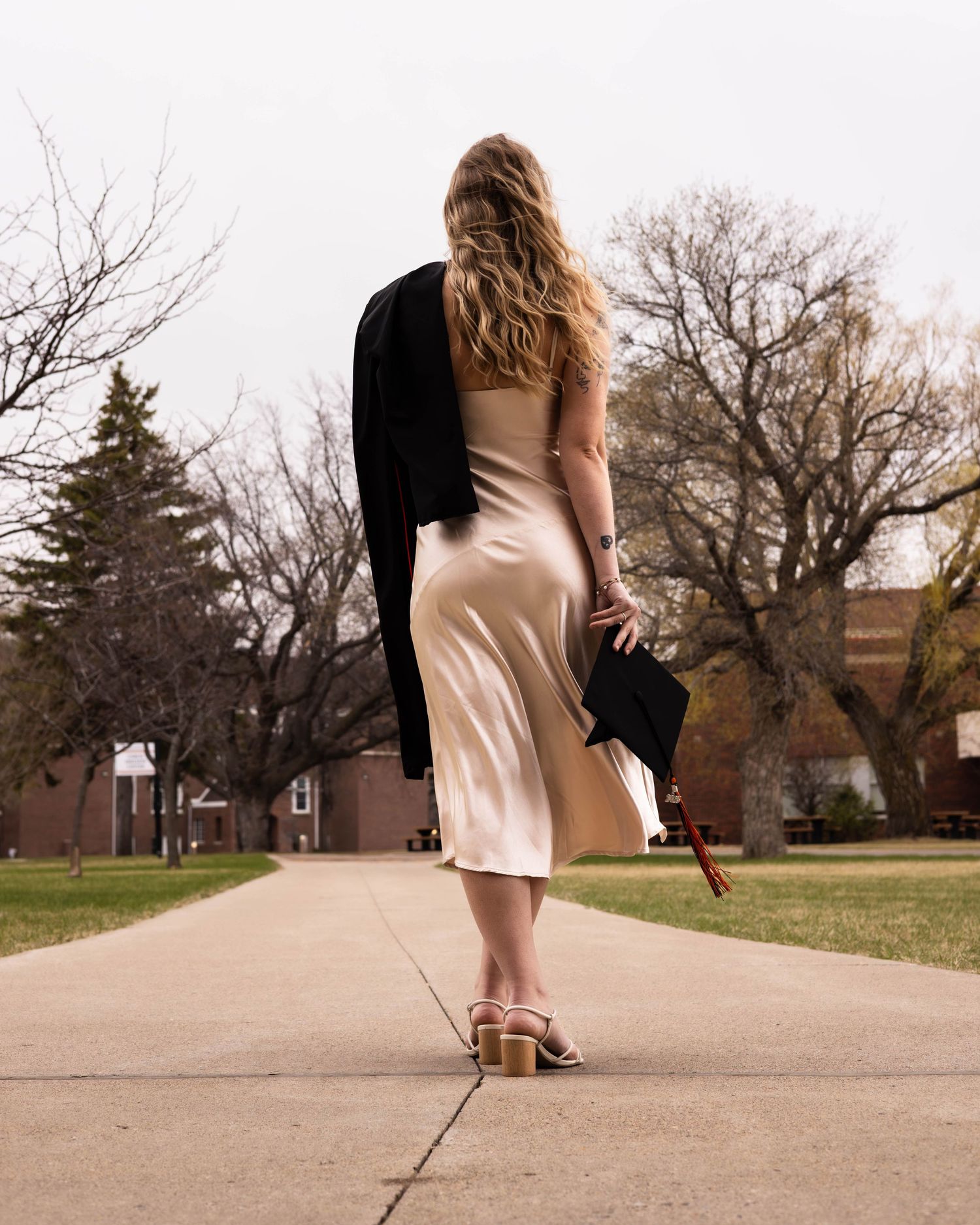 Low angle view of someone walking on a concrete path through a park campus.