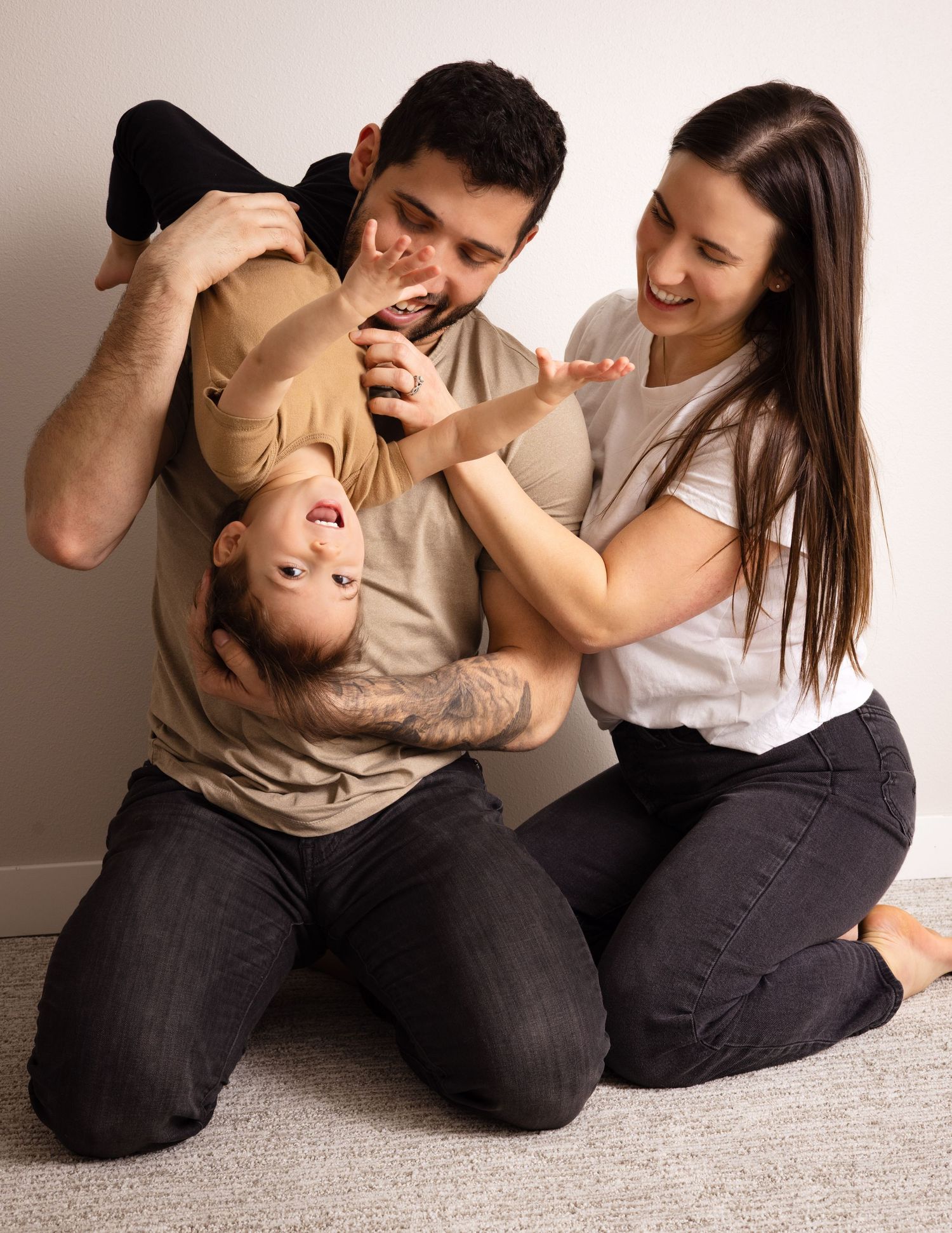 A couple shares playful laughter while sitting together on a carpeted floor.