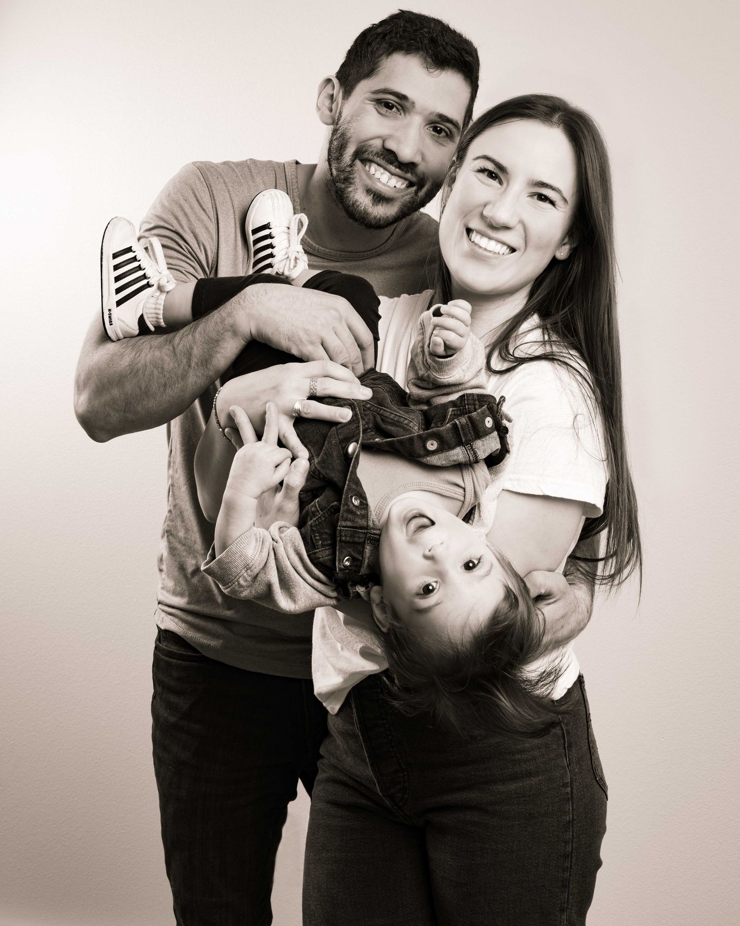 Black and white studio portrait capturing candid family laughter.