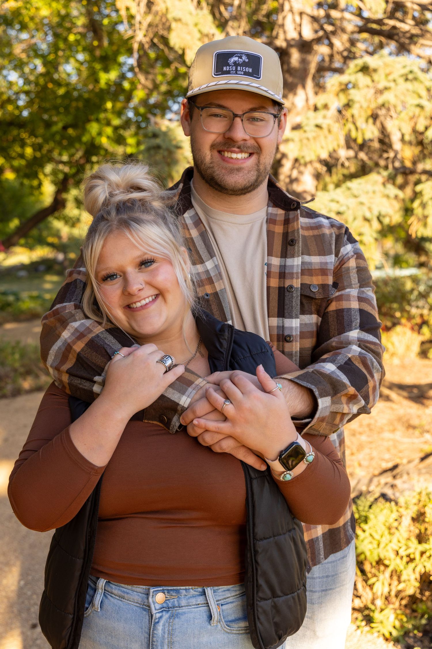Couple in casual autumn attire embracing outdoors during golden hour.