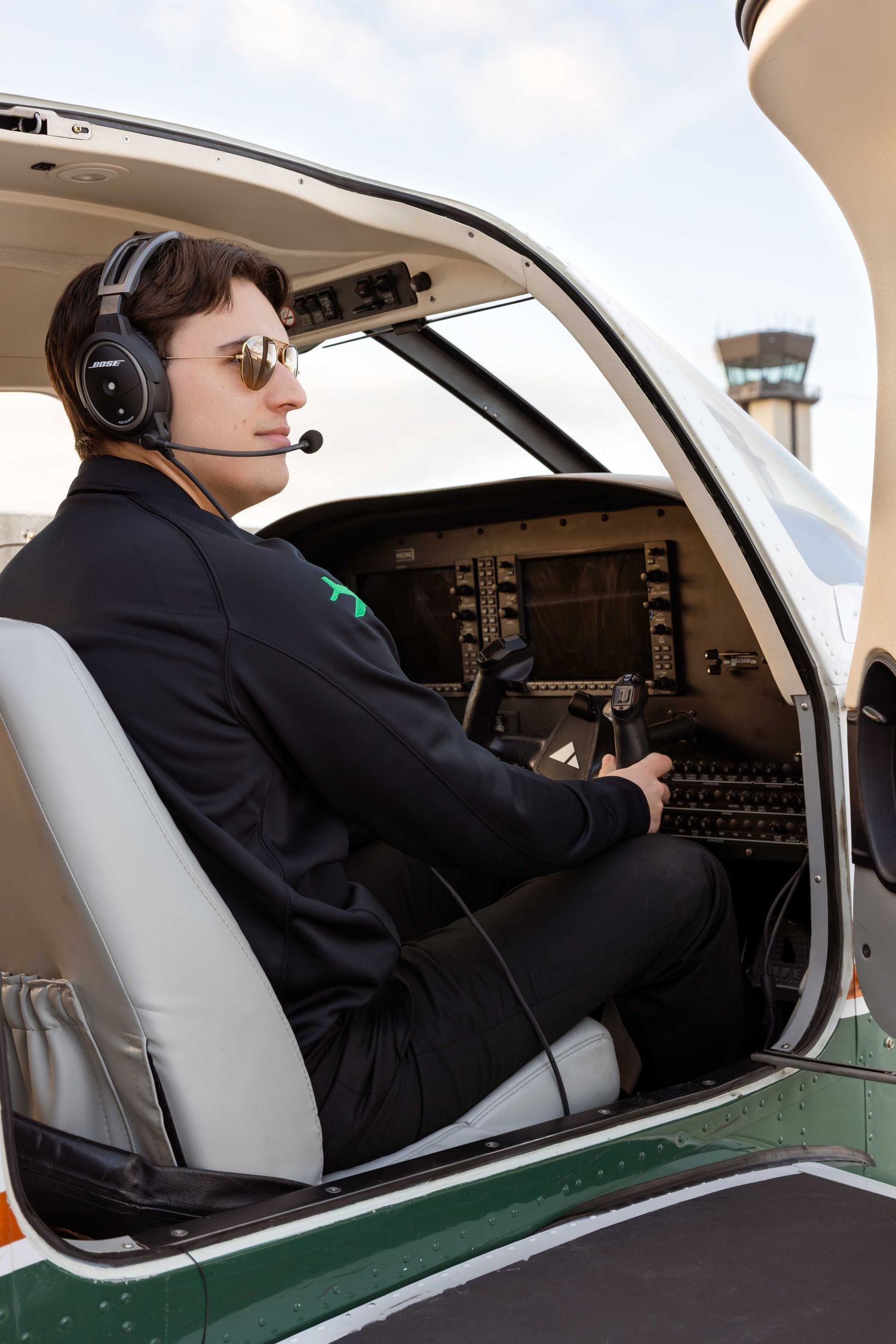 Professional pilot in cockpit wearing headset while operating aircraft controls during flight.