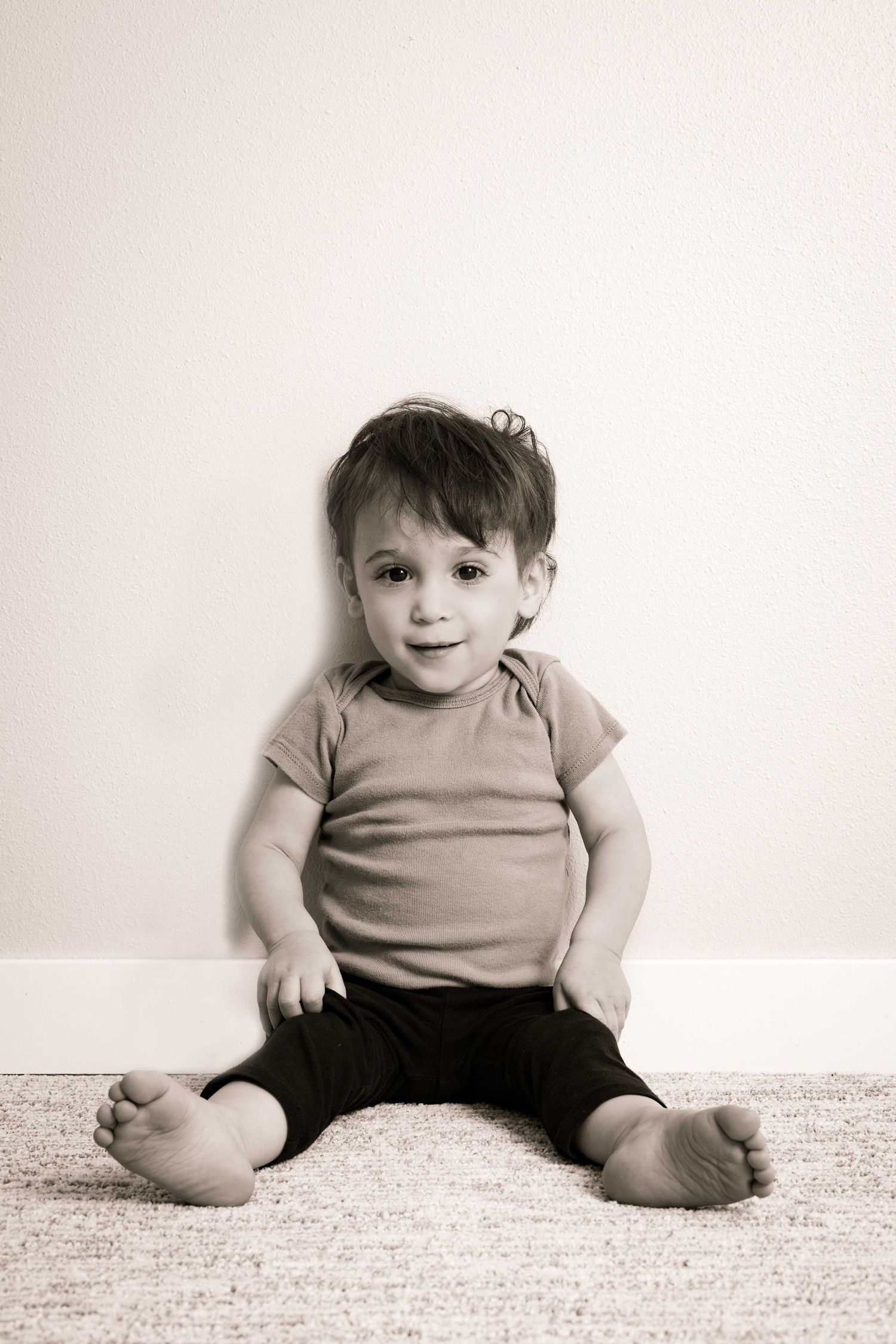Black and white photo sequence of a baby sitting on carpet in a light colored shirt.