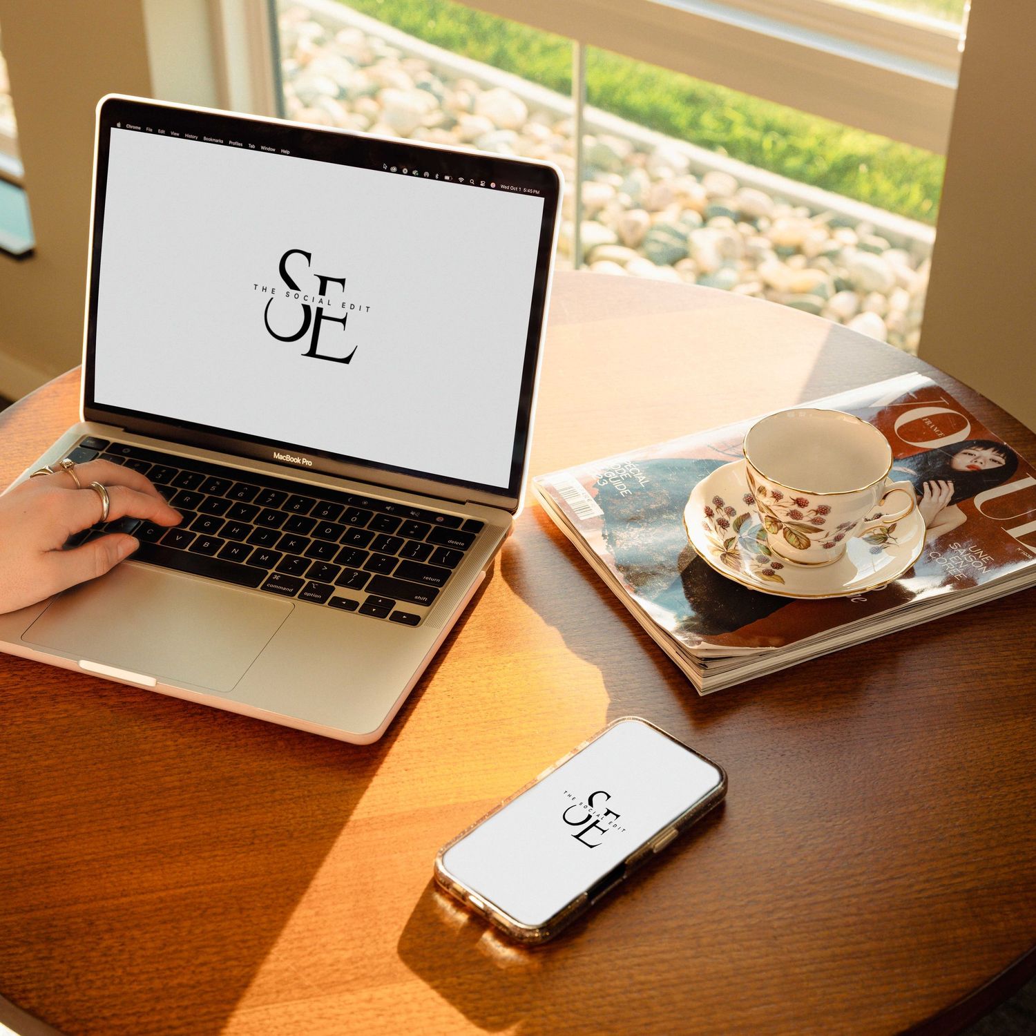 Laptop and coffee cup on wooden desk with natural sunlight streaming through window.