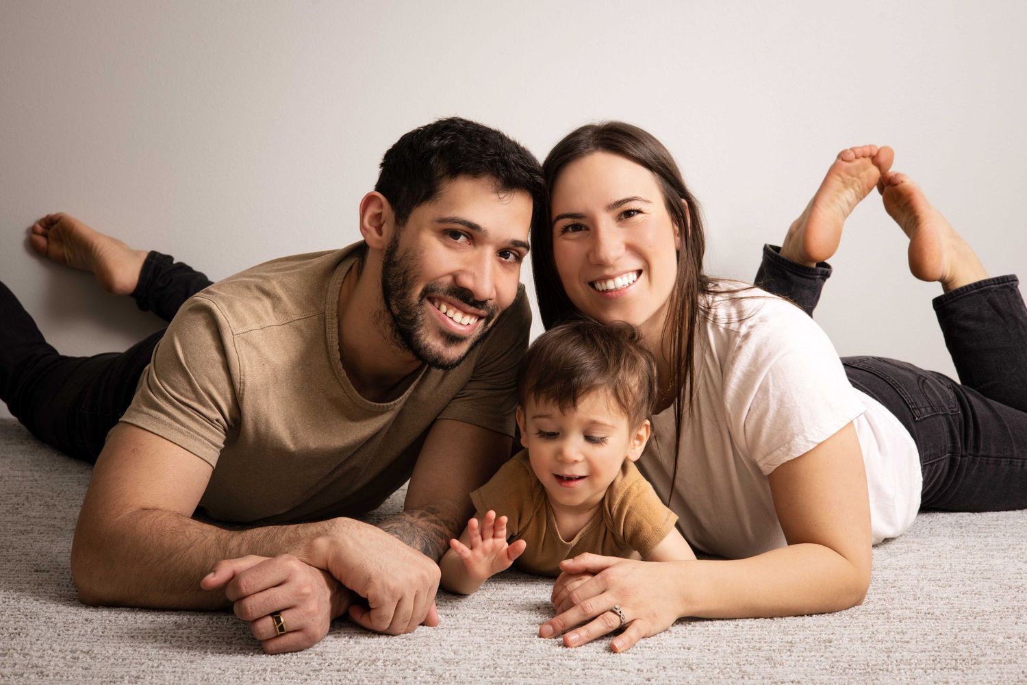 A candid family portrait showing everyone lying on carpet and laughing together.