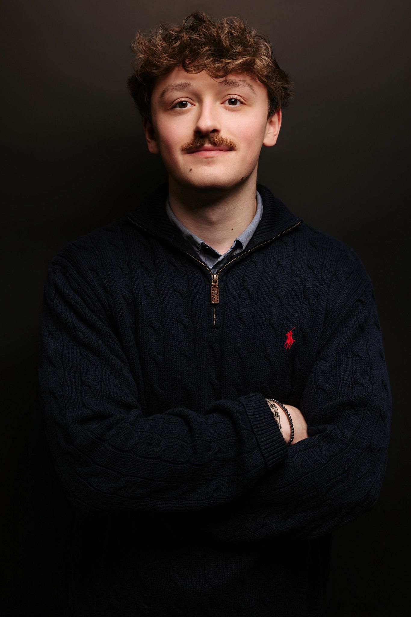Studio portraits in dark jacket against black background.