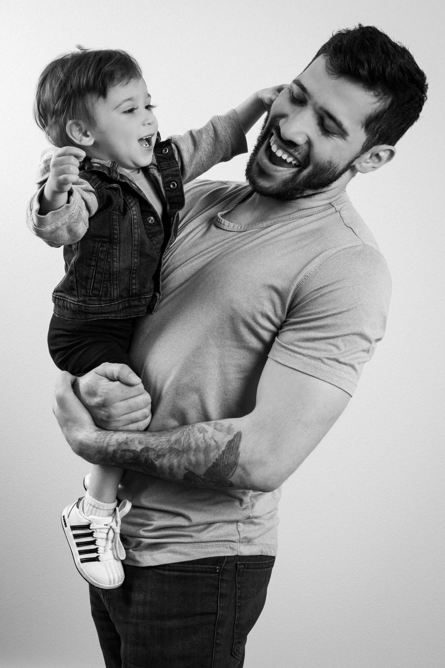 A joyful black and white portrait of a parent and child sharing an energetic laugh together.