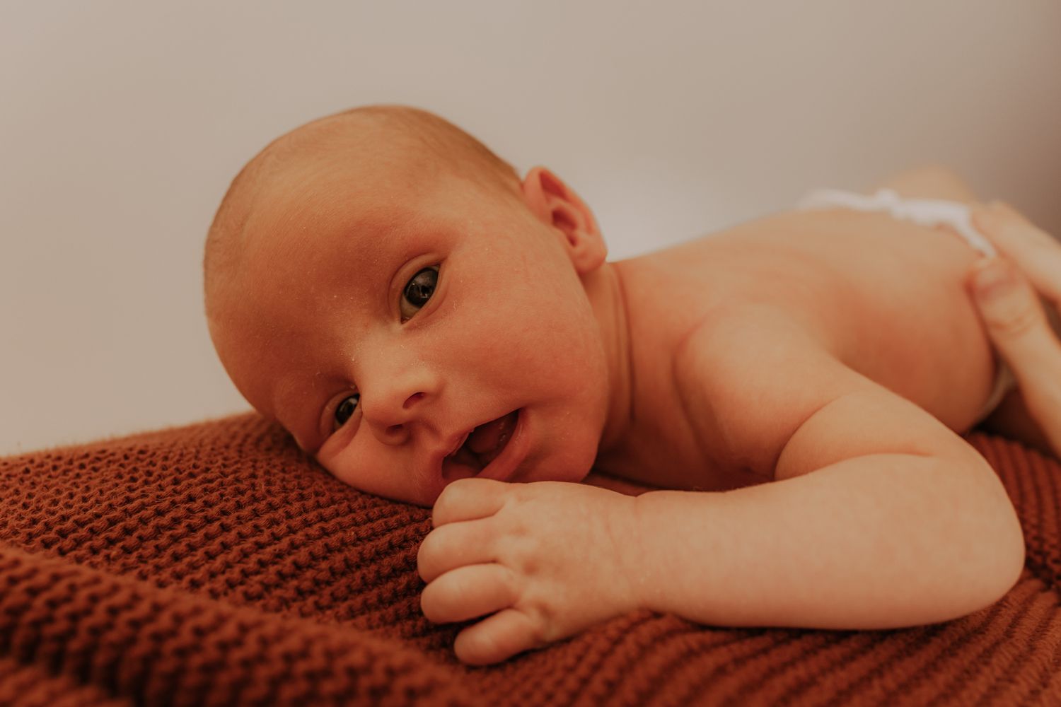 A series of connected images showing a newborn baby lying on a brown knitted blanket.