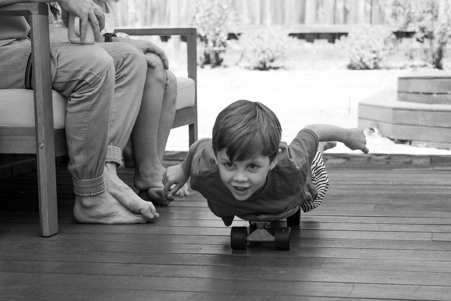 A sequence of black and white photos showing someone playfully peeking through wooden deck boards.