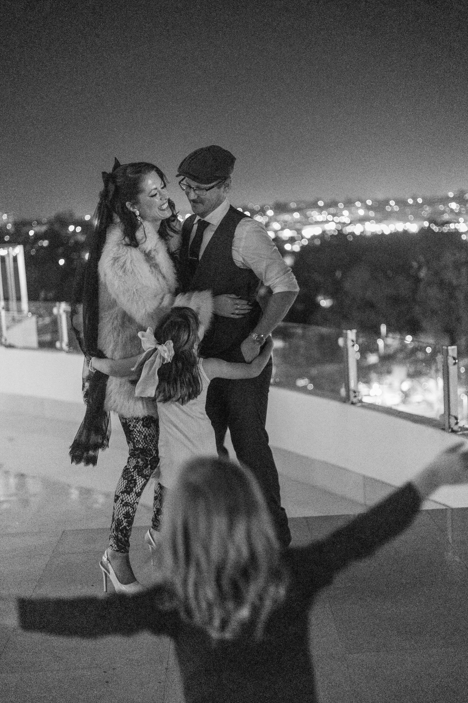 A romantic black and white sequence of a couple dancing together at night with city lights in the background.