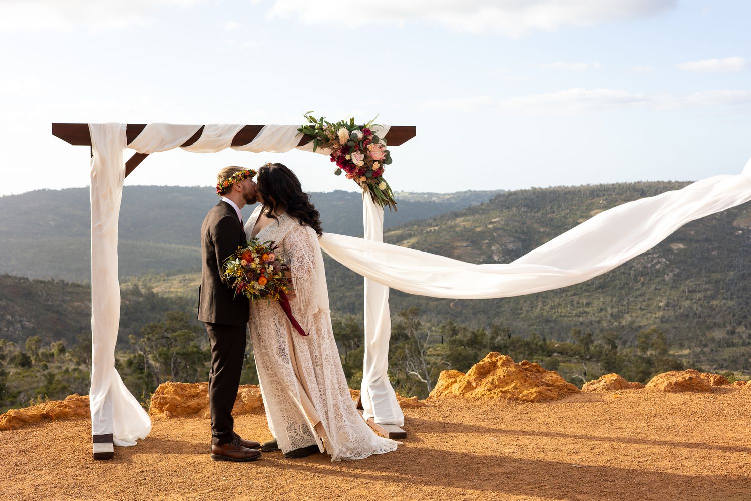 Wedding couple on hilltop with flowing veil against mountain landscape. Perth wedding documentary photography, elopement