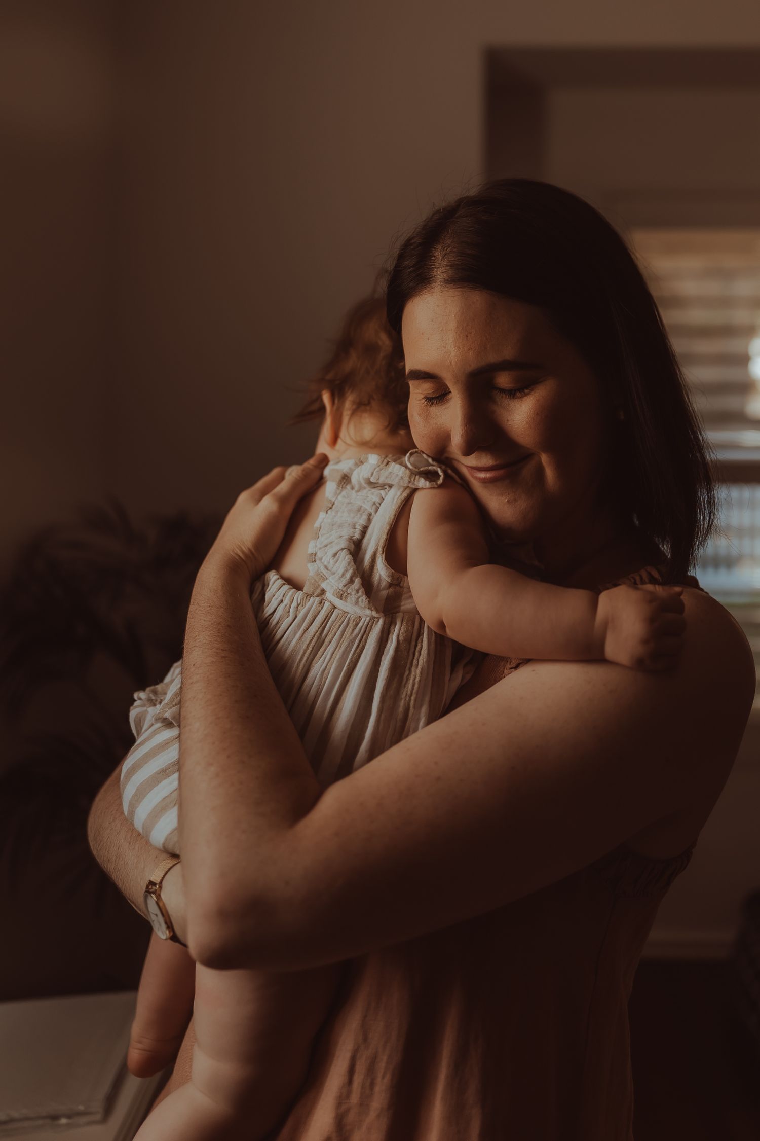Two people share an intimate embrace in warm, moody lighting with a soft, romantic atmosphere.