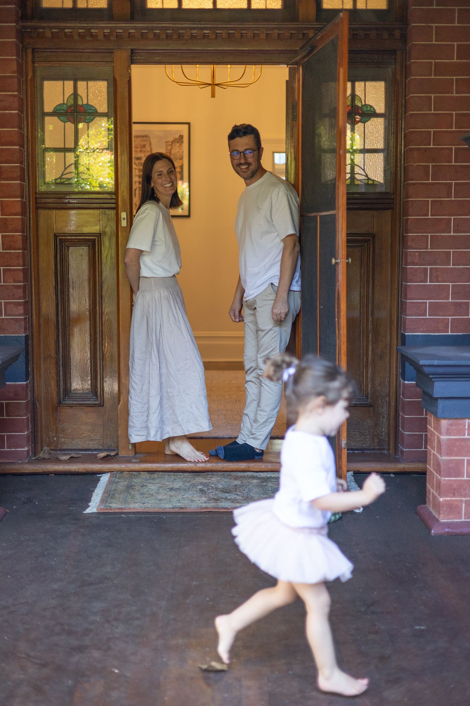A playful scene unfolds on a brick porch with flowing white dress. Perth in home documentary family photography Fremantle