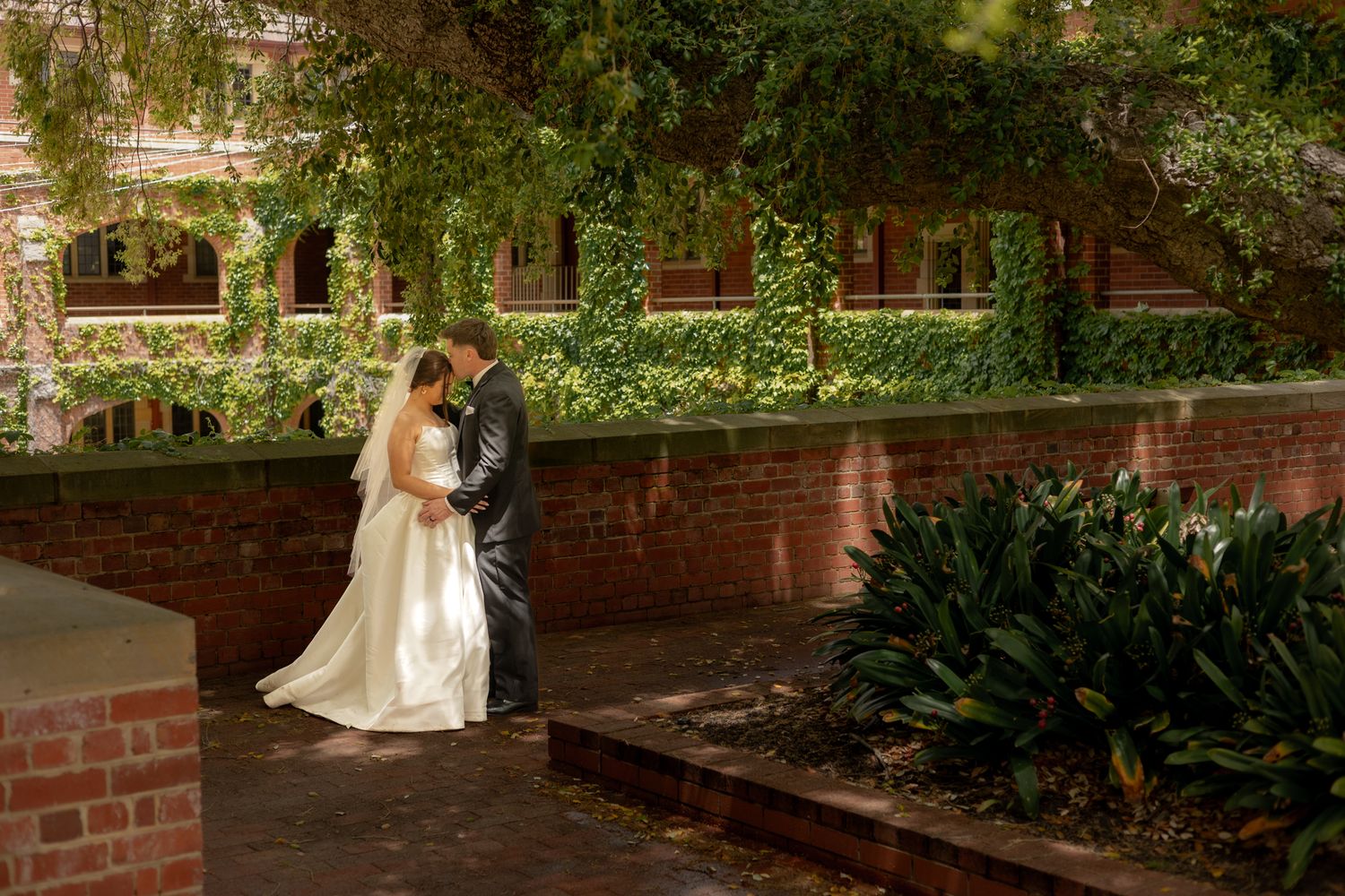 Wedding couple in garden setting with brick walls and lush greenery. Perth wedding documentary photography, elopement