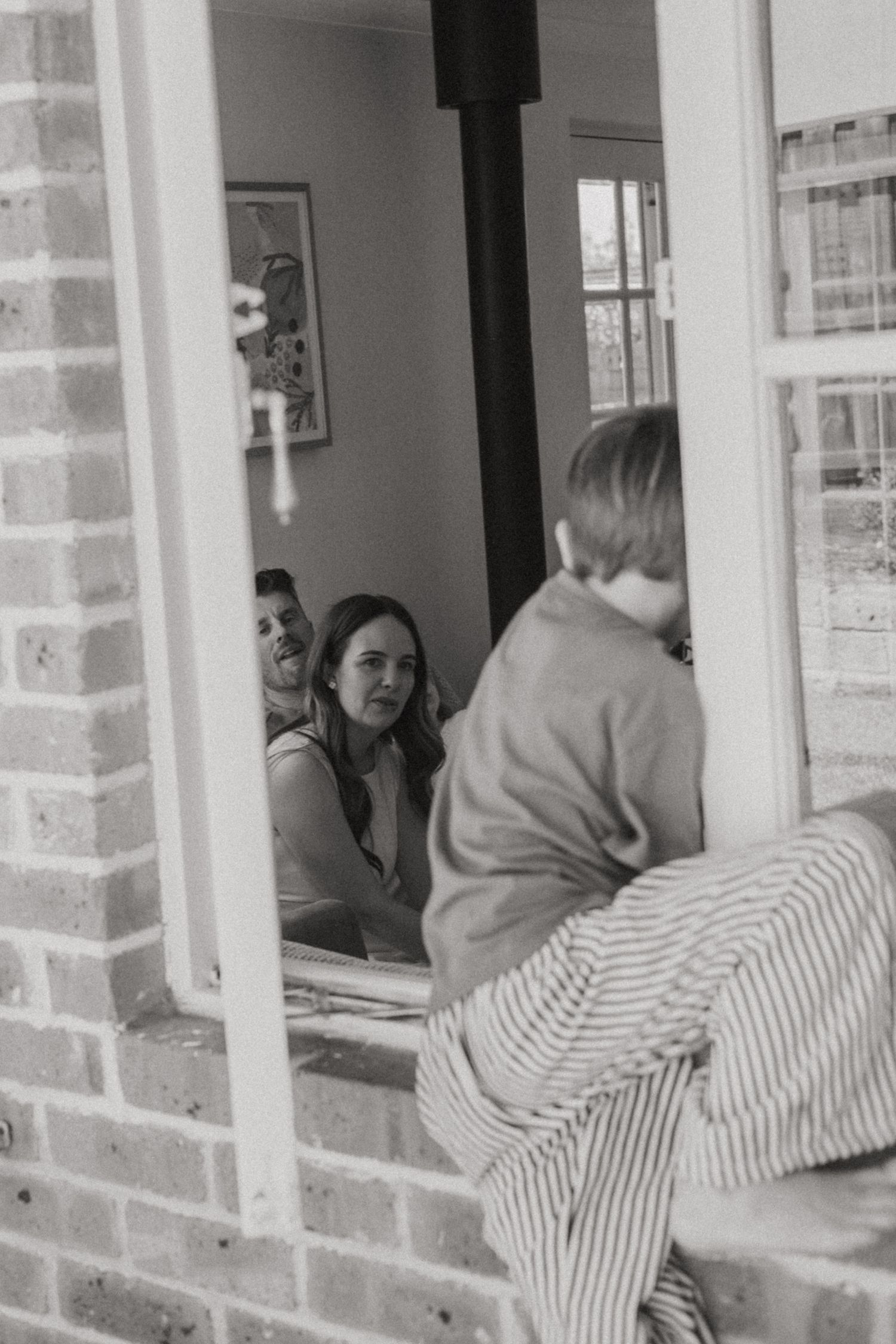 A black and white photo sequence shows a person peeking through a window in four progressive frames.
