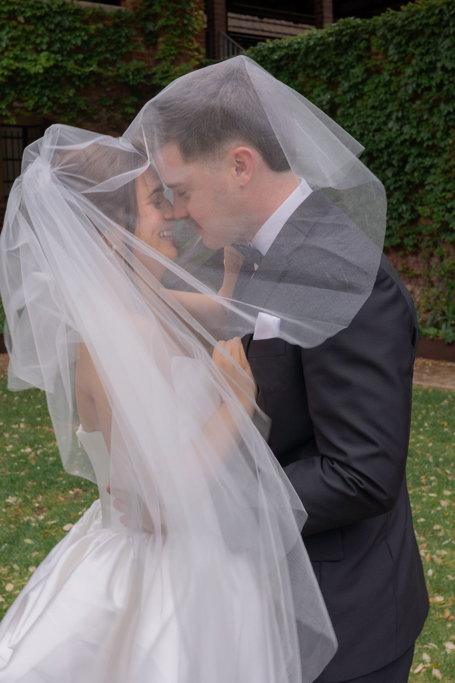 A romantic wedding moment captured in a sequence of five photos showing a couple sharing a kiss under a flowing veil outdoors.