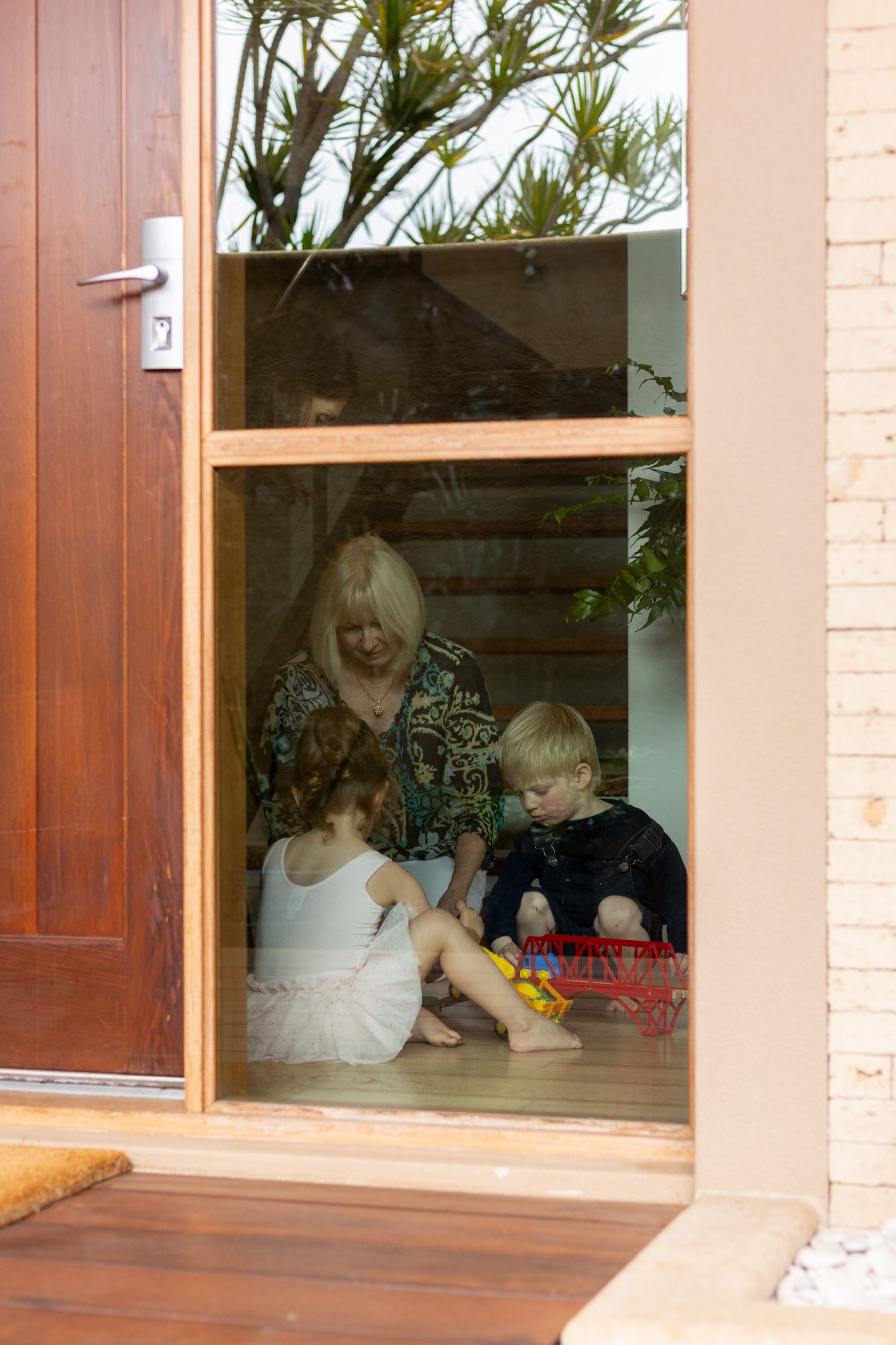 Family members gather by a window enjoying time together indoors. Perth in home documentary family photography