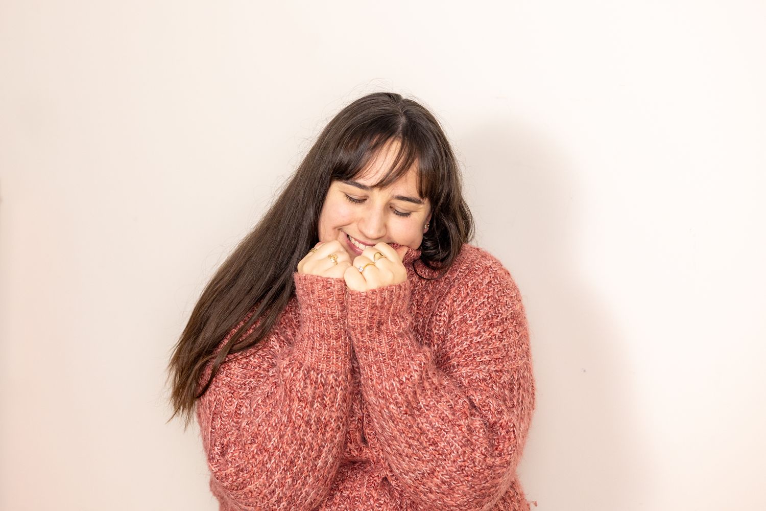 Woman in cozy pink sweater laughing and expressing joy in casual portrait series.