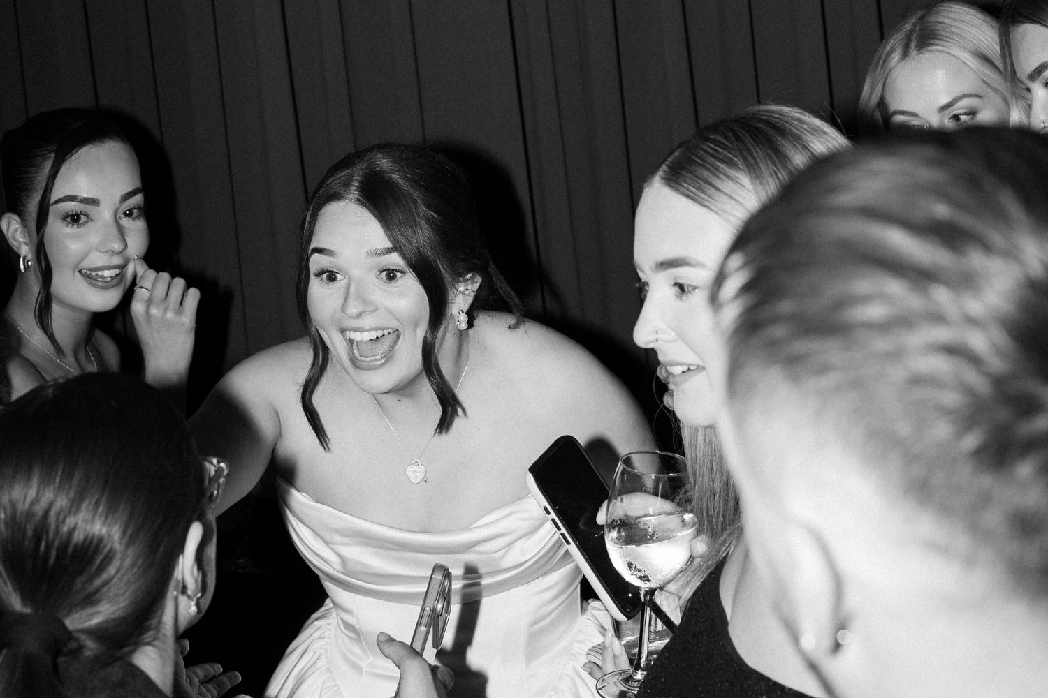 Black and white photo showing a joyful moment at a party with people laughing and holding drinks.