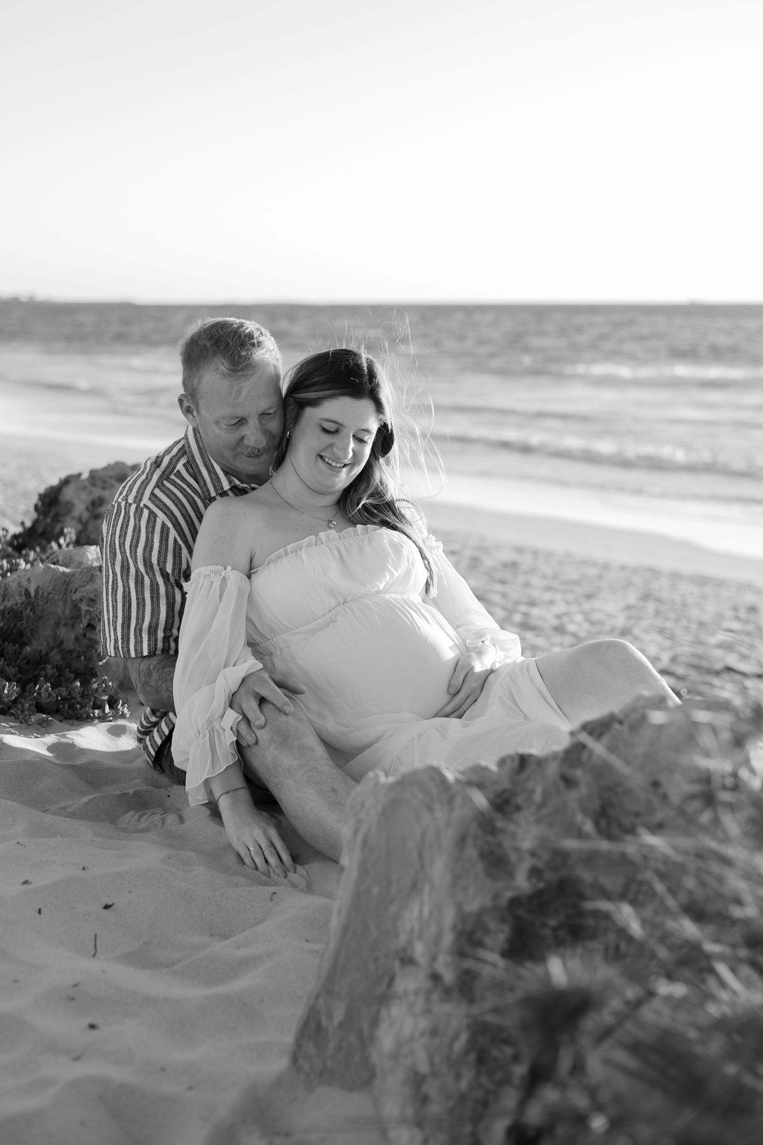 A romantic couple embraces on a sandy beach in black and white. Perth Maternity Photography Fremantle