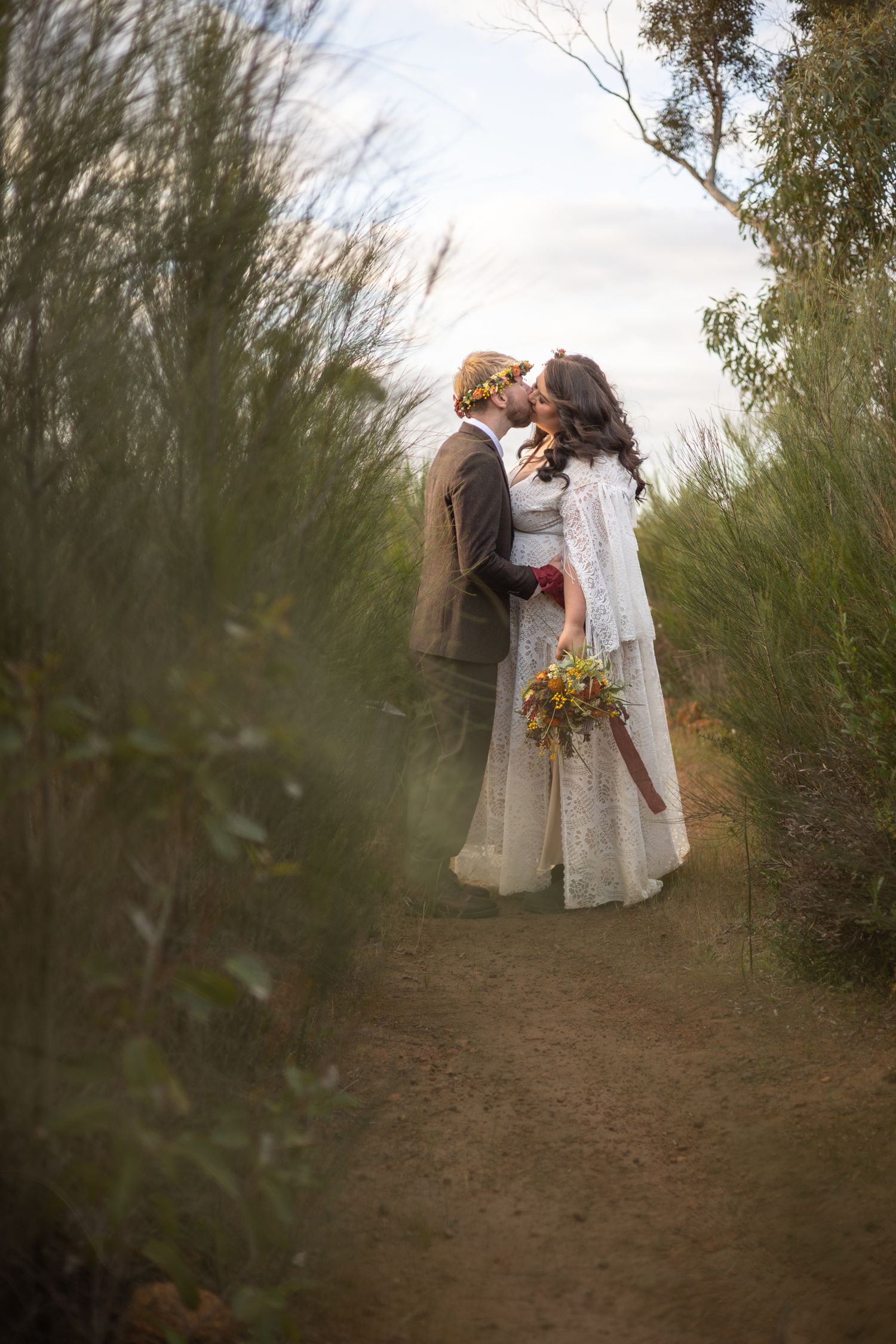 A romantic wedding couple embracing on a nature path surrounded by tall grass. Perth wedding documentary photography, elopement