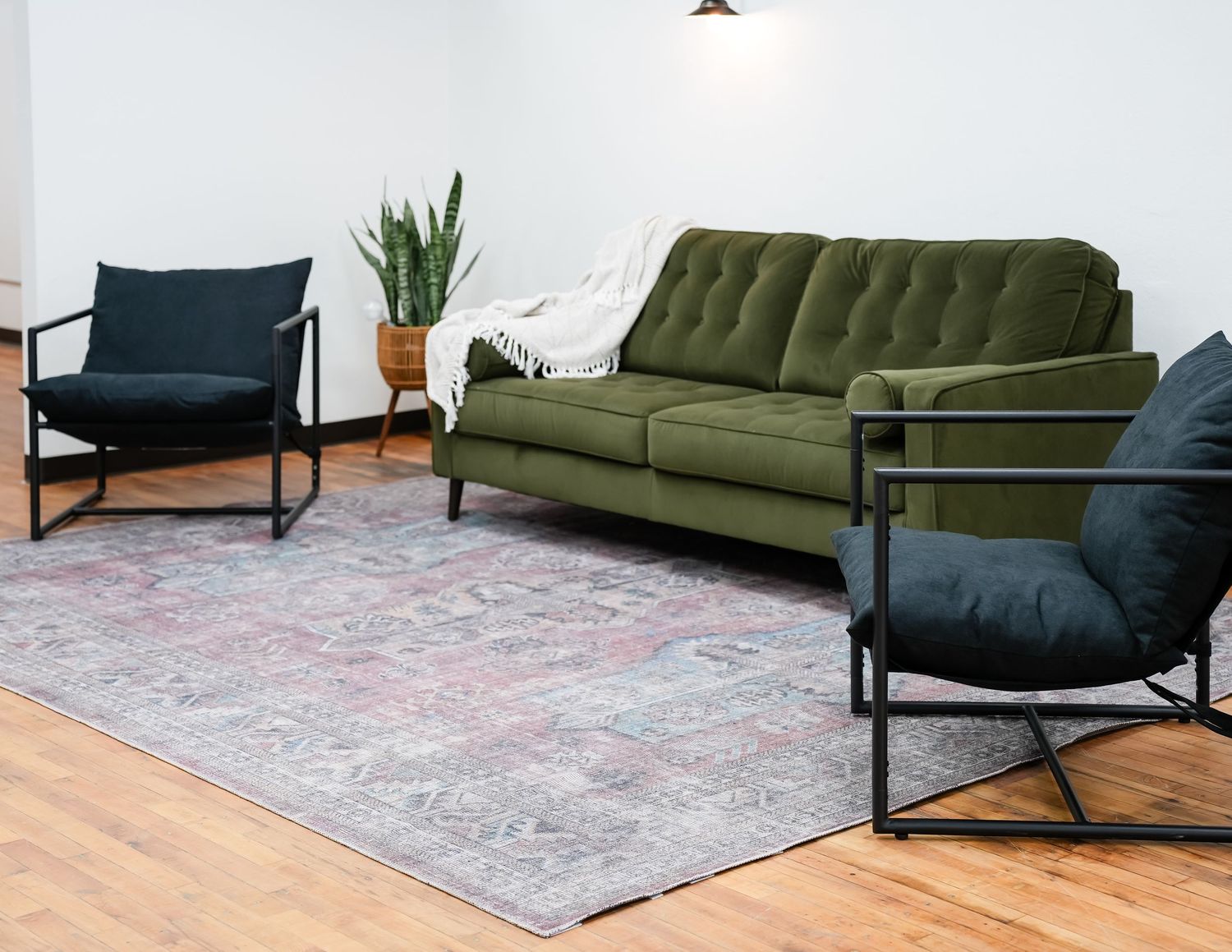 Green couch, black chairs, and industrial rugs at Spotlight Studio in Huron SD, styled for gatherings, parties, and event space rentals.