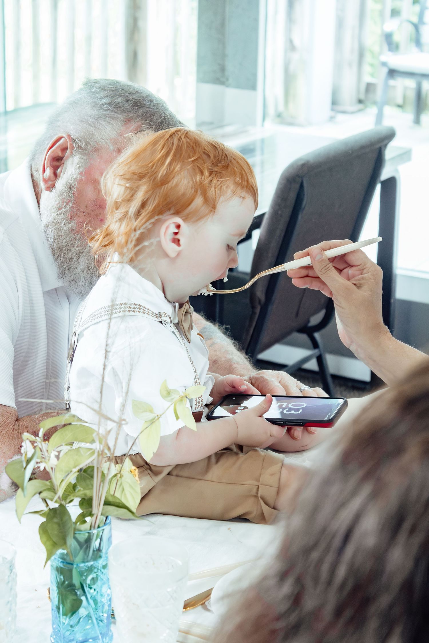 A family moment captured at a dining table with a blue vase of flowers in the foreground.