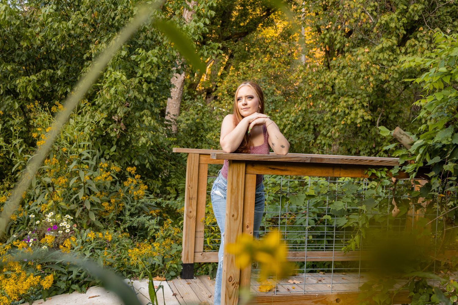 Garden photoshoot setup with wooden bench surrounded by lush greenery.
