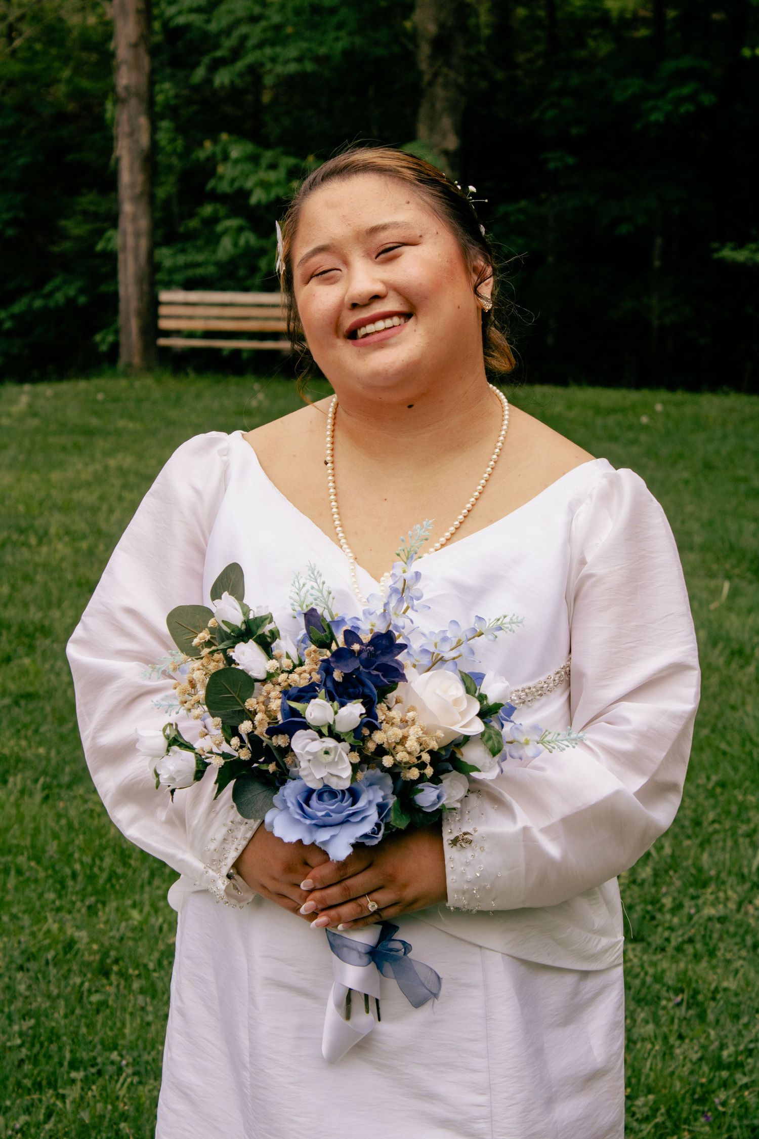 Bride holding a beautiful bouquet featuring blue and white flowers with delicate greenery.