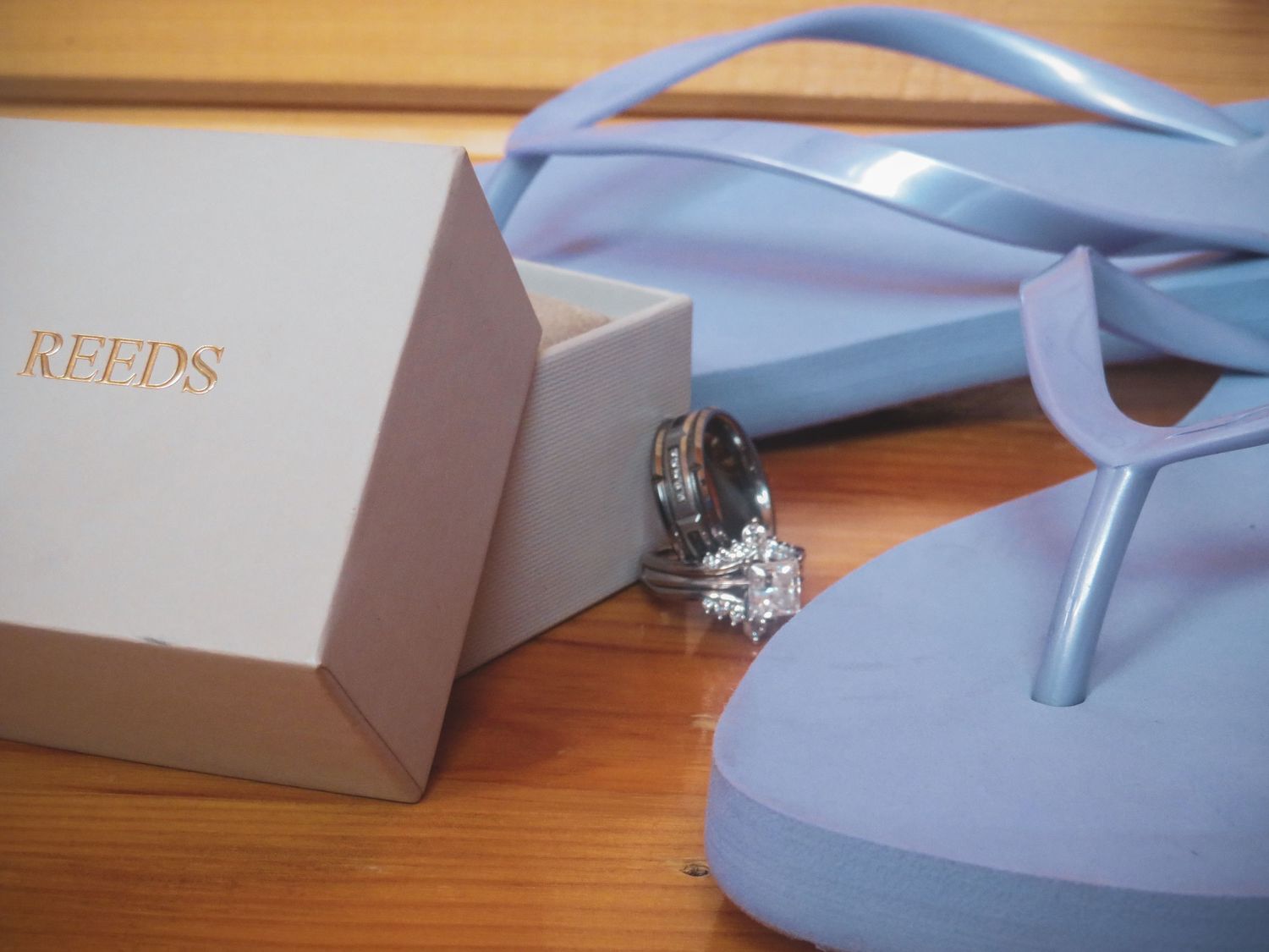 Wedding rings and accessories displayed with light blue ribbons and packaging.