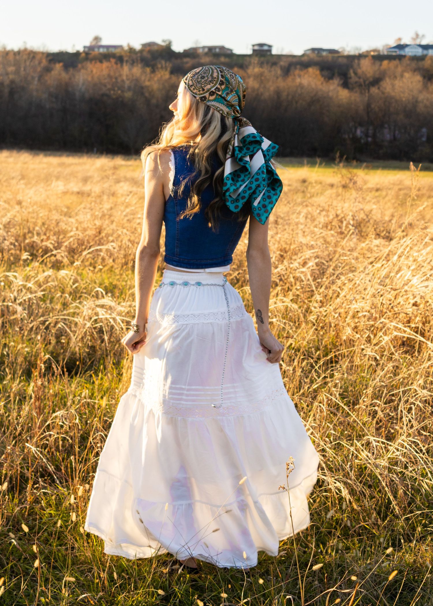 White layered dress swirls gracefully in a golden wheat field during sunset.