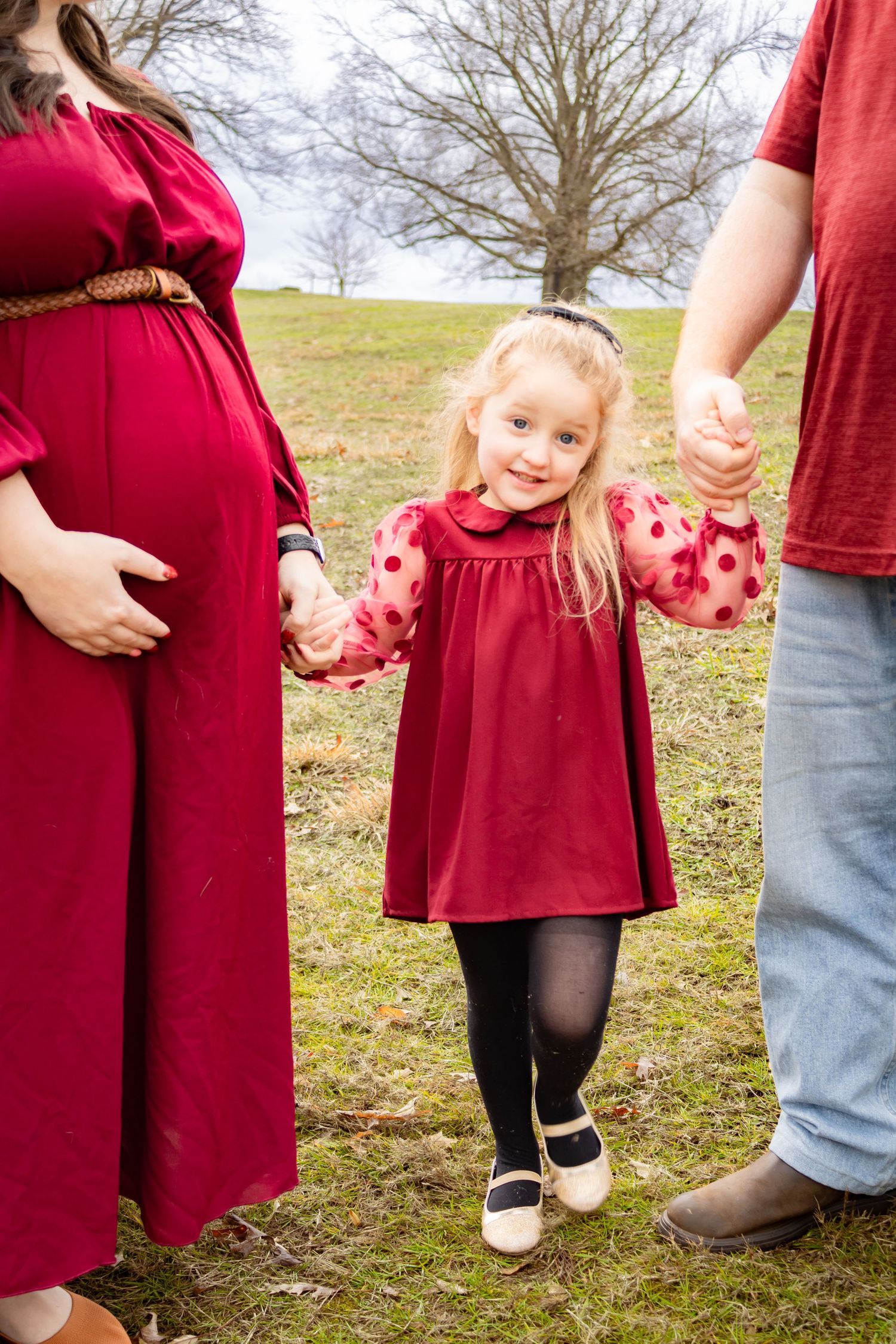 People in red dresses standing together on a hillside.