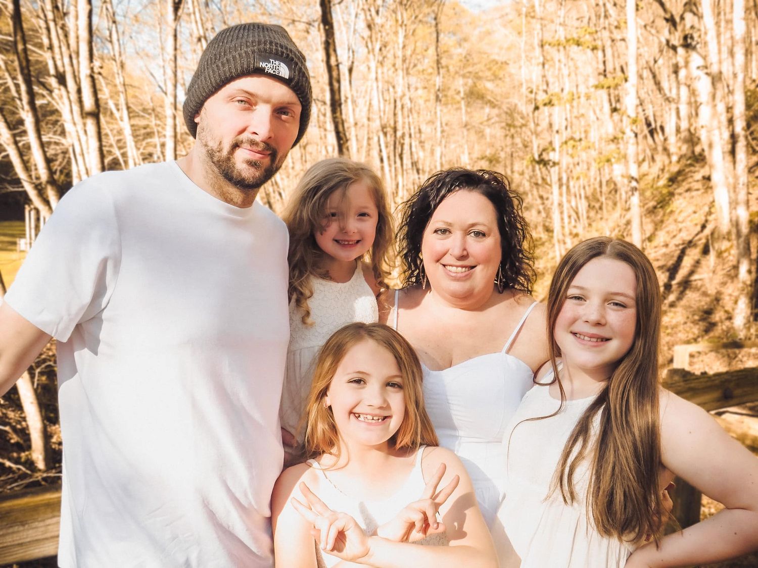 Casual family photo session with natural lighting and autumn trees in background.