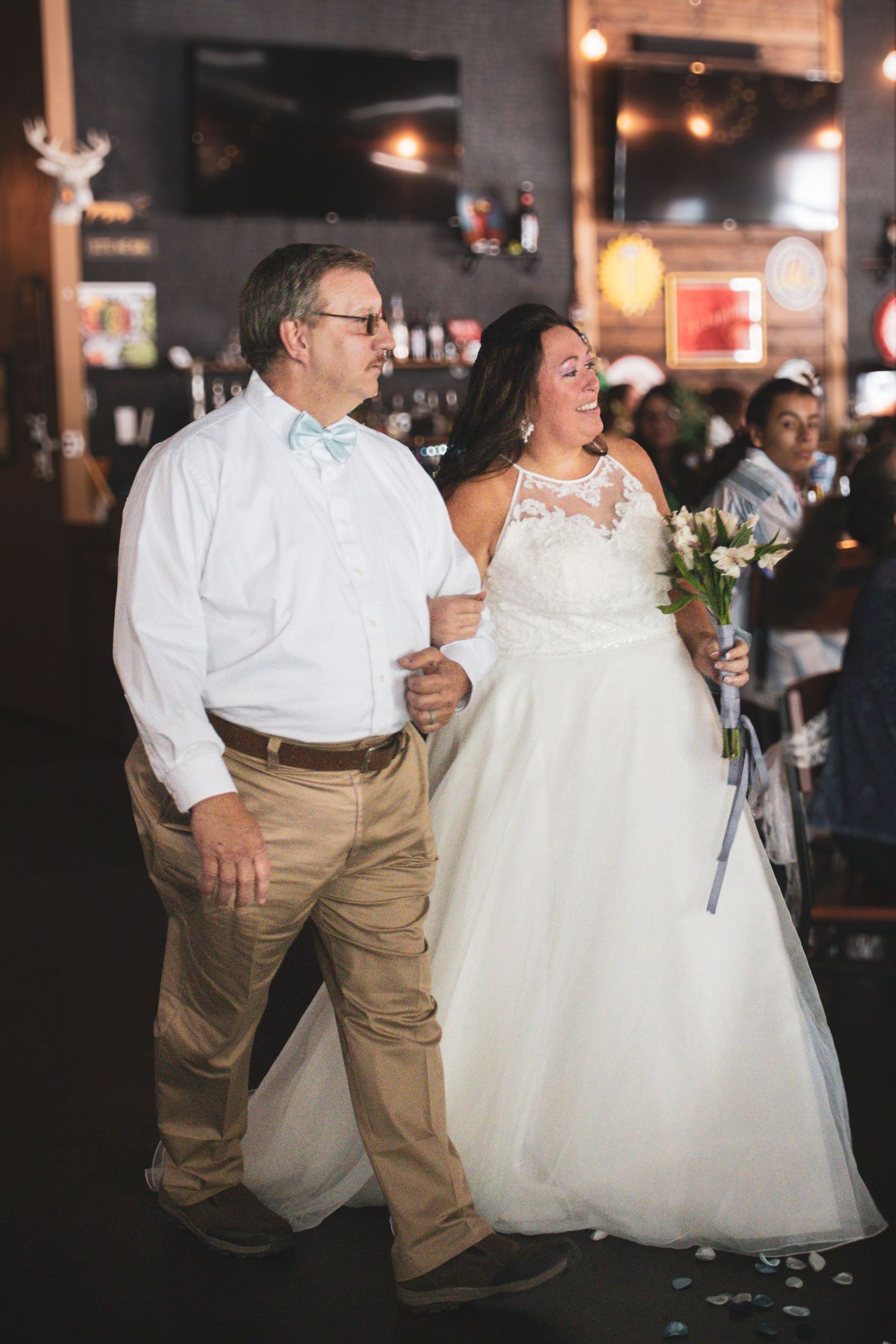 Wedding couple shares a joyful moment during reception in dimly lit venue.