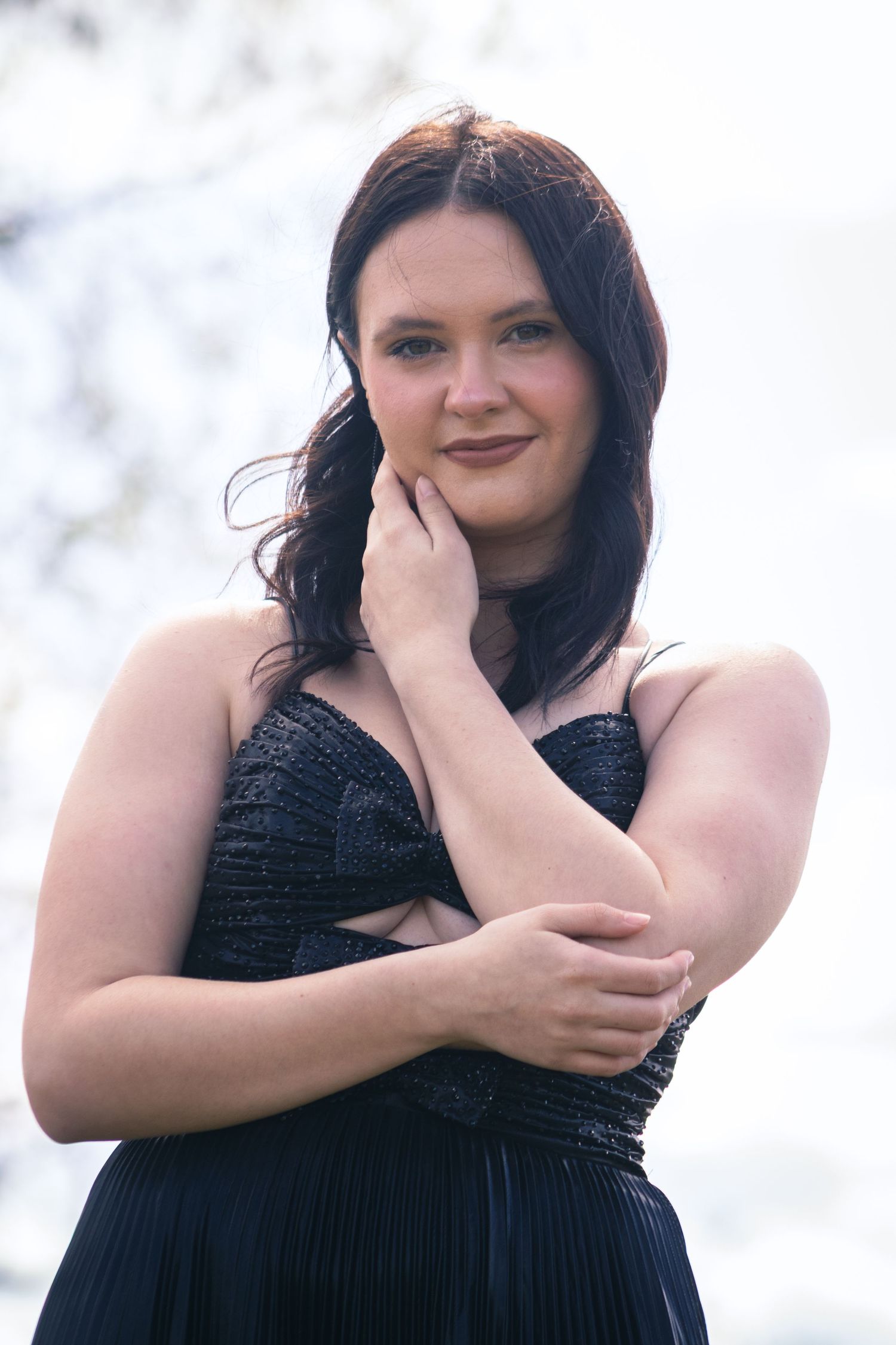 Woman in black evening dress poses elegantly against white background in photo series.