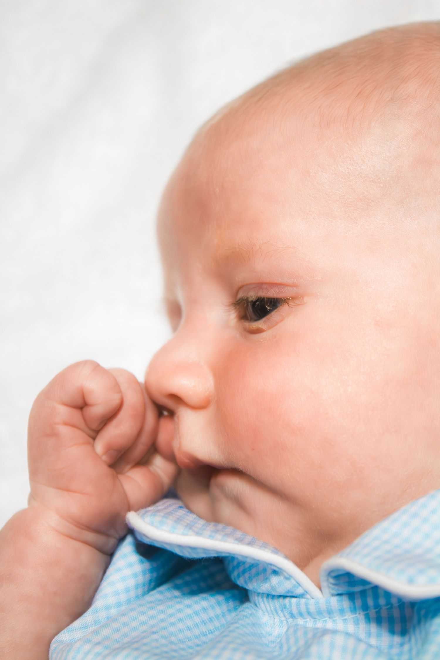 Close-up profile view of a baby wearing a light blue outfit.