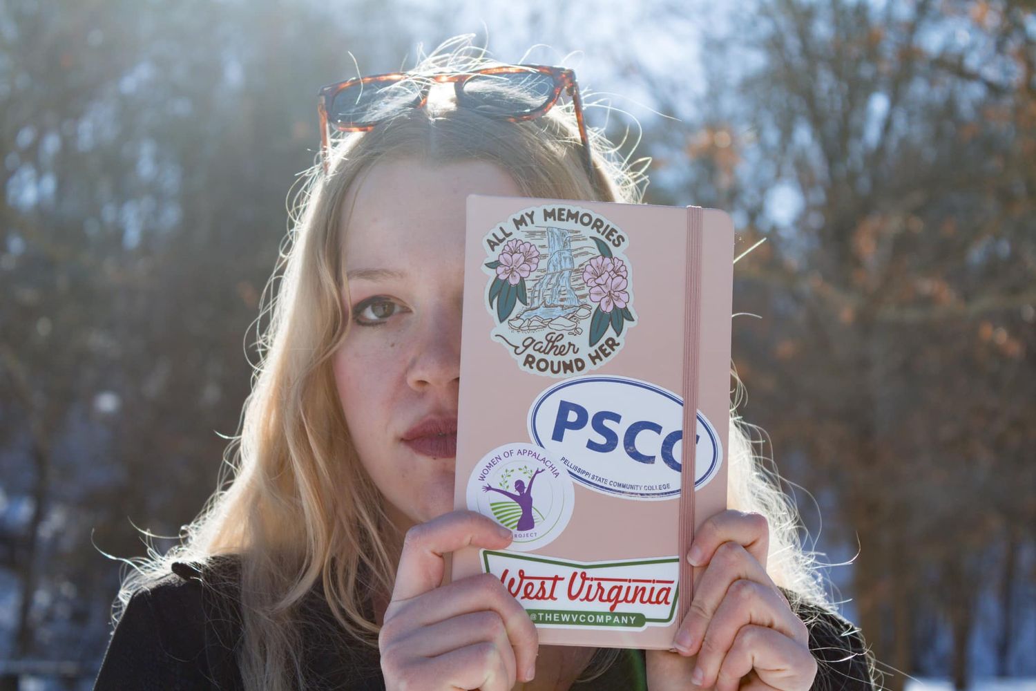 A pink PSC logo being held up against a natural outdoor background with trees.