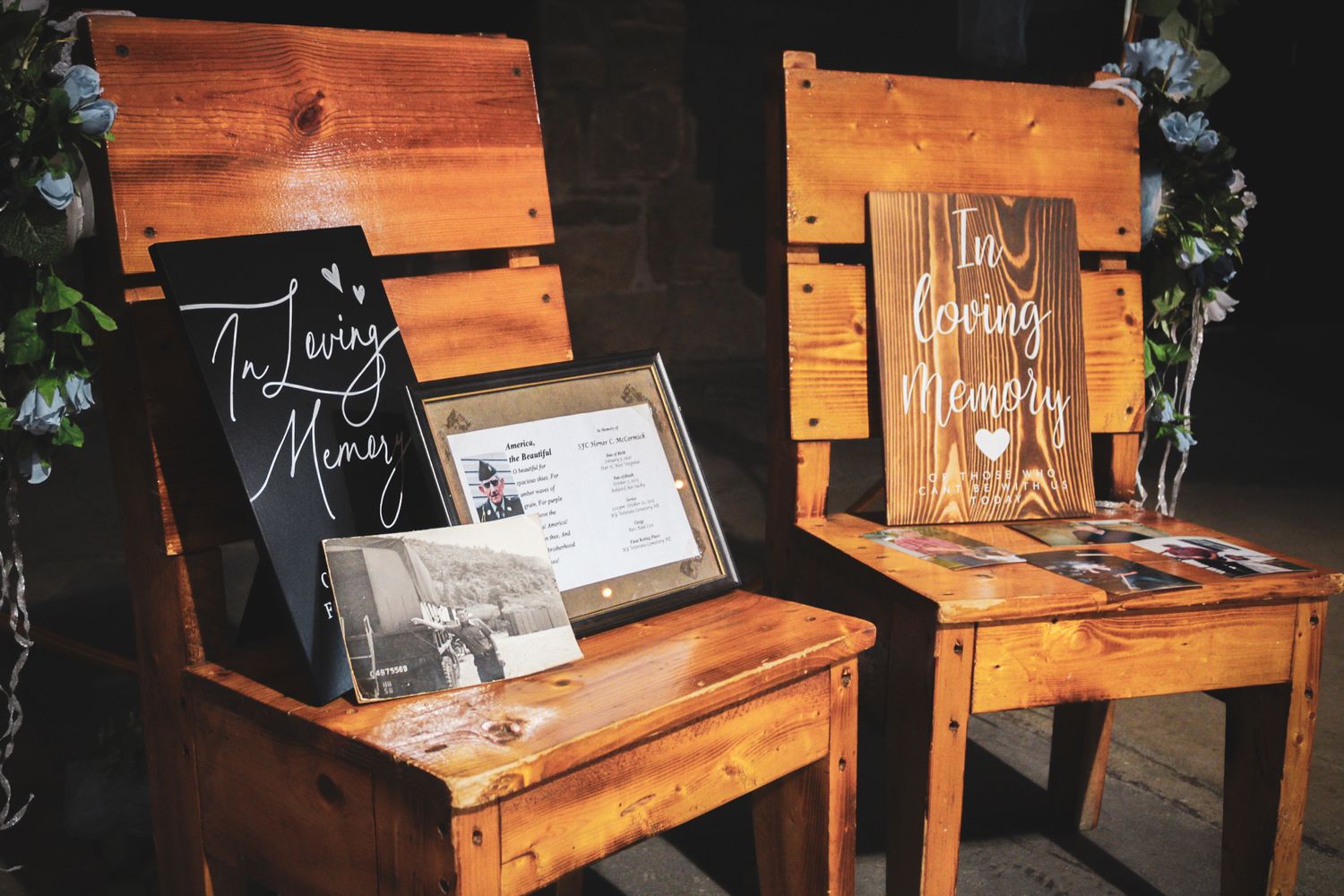 Rustic wooden benches with wedding signage and decorations at an outdoor ceremony.