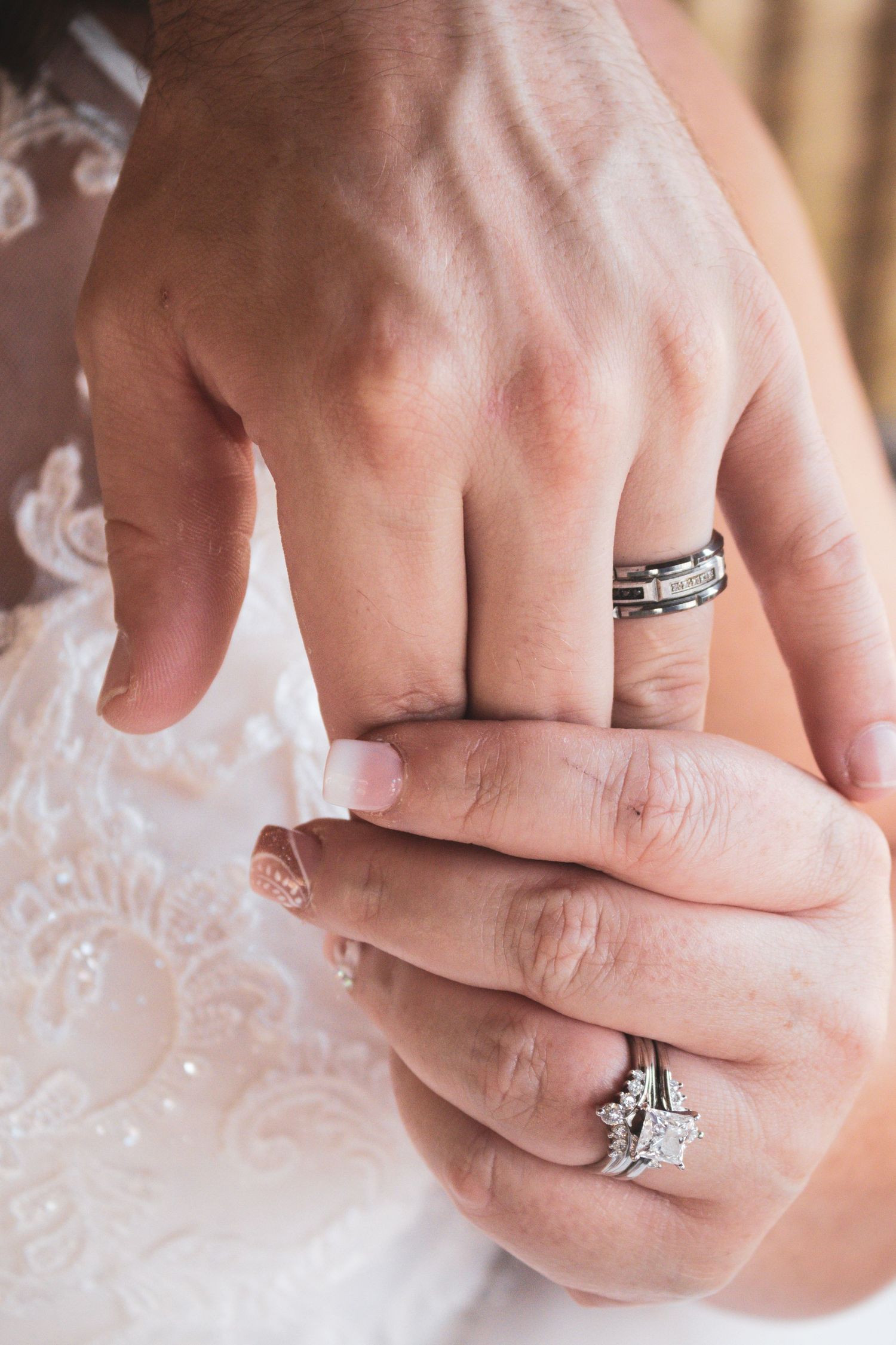 Close-up shots of wedding rings and hands against white lace fabric.