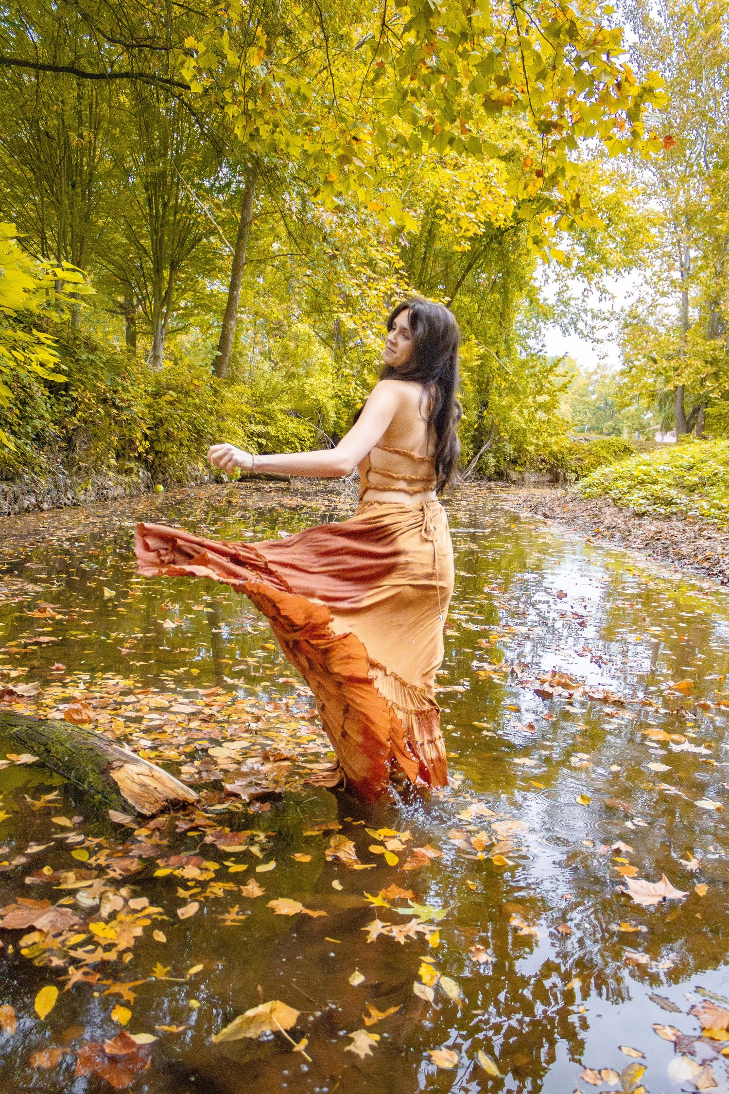 Artistic portrait series showing flowing orange dress movement against autumn water reflections.