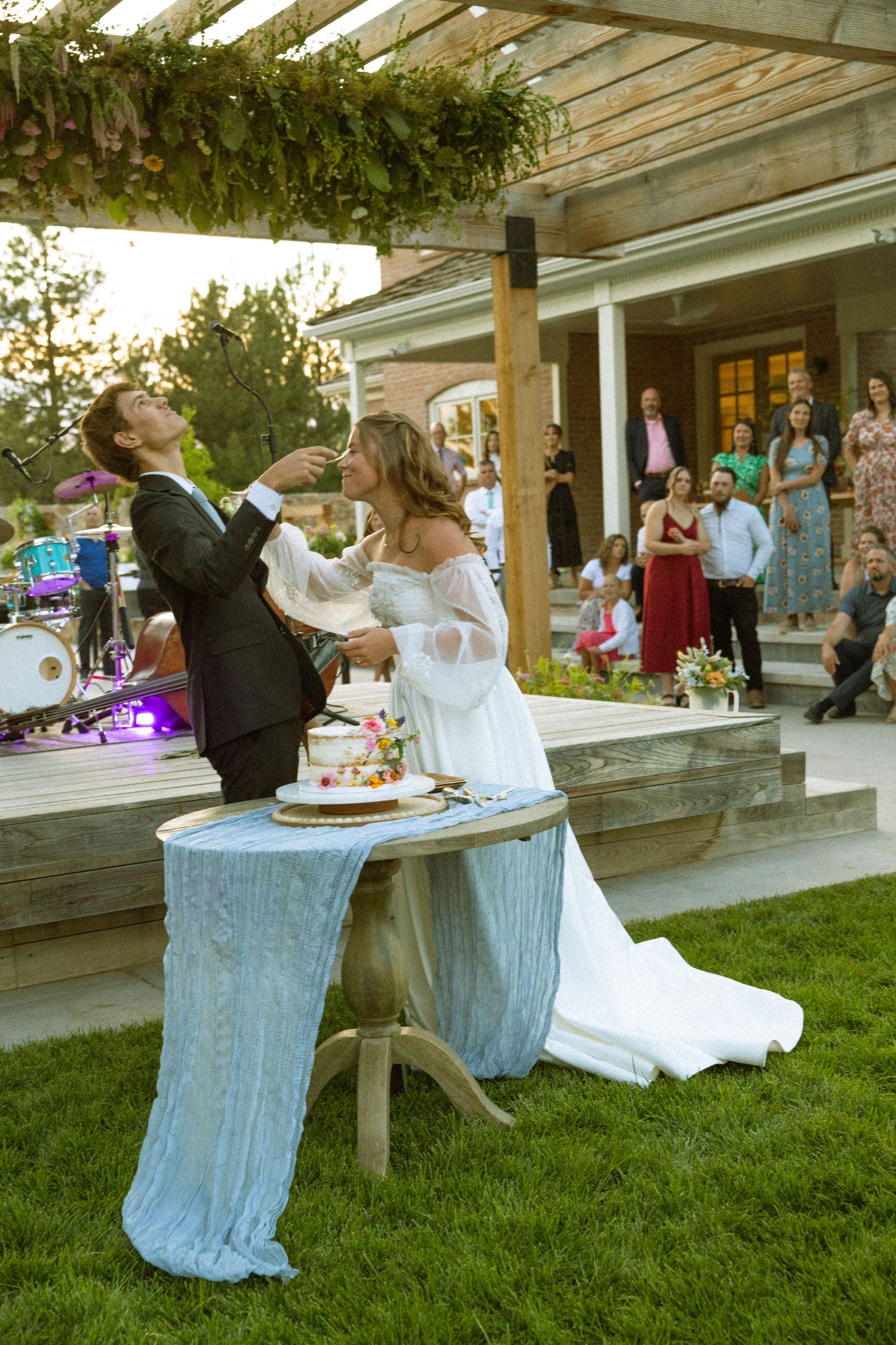 A playful wedding cake smashing moment captured during an outdoor reception.