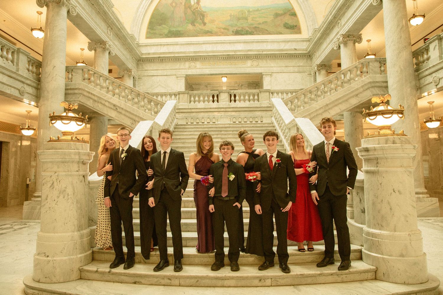 A panoramic view of a formal gathering in an ornate marble-columned hall with chandeliers and classical architecture.