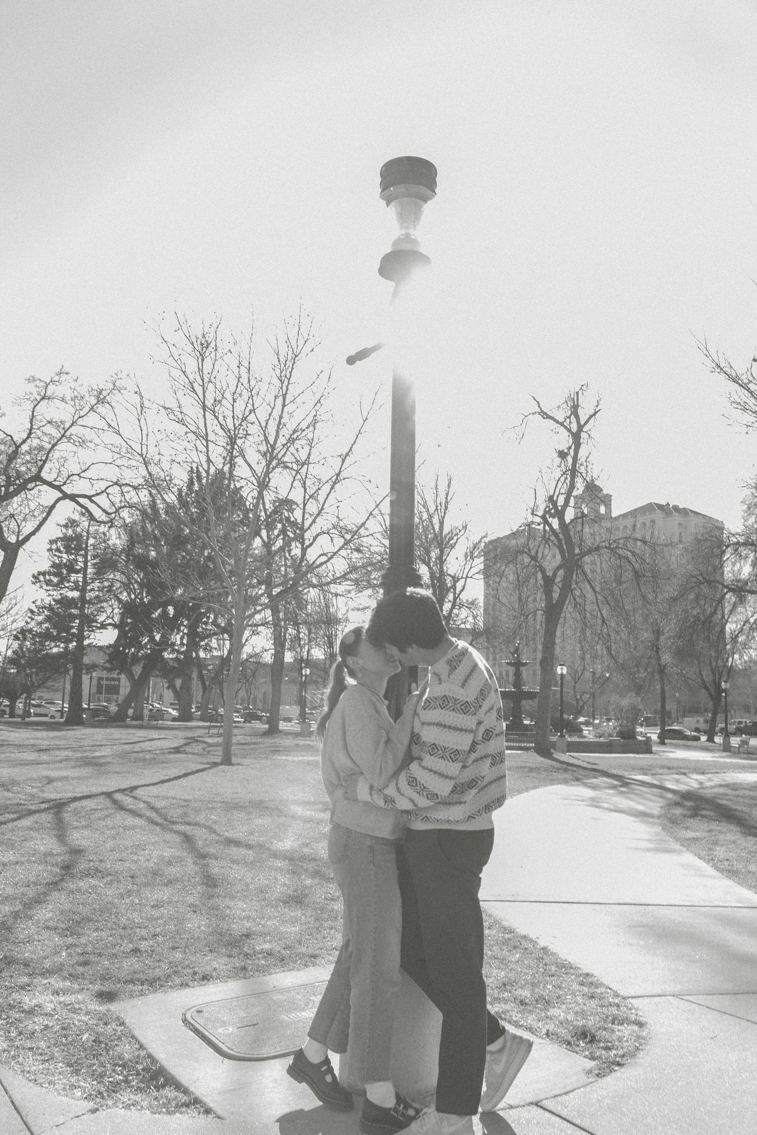 A vintage black and white photo series showing a couple walking and embracing in a park setting on a winter day.