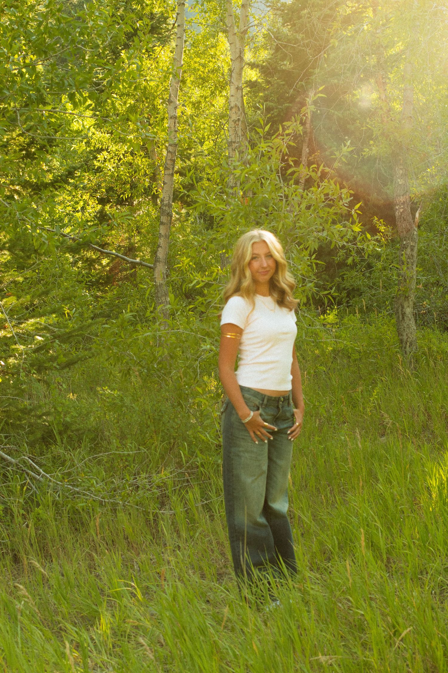 Candid summer portrait in a sunlit meadow with lush green foliage.