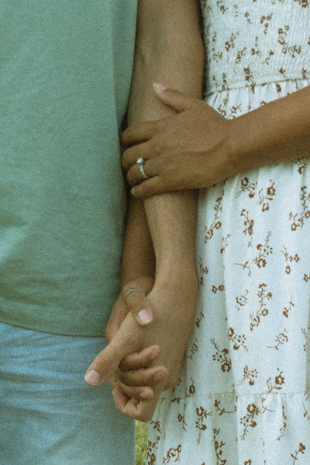 A series of hands holding each other in a row against a green and white floral background.
