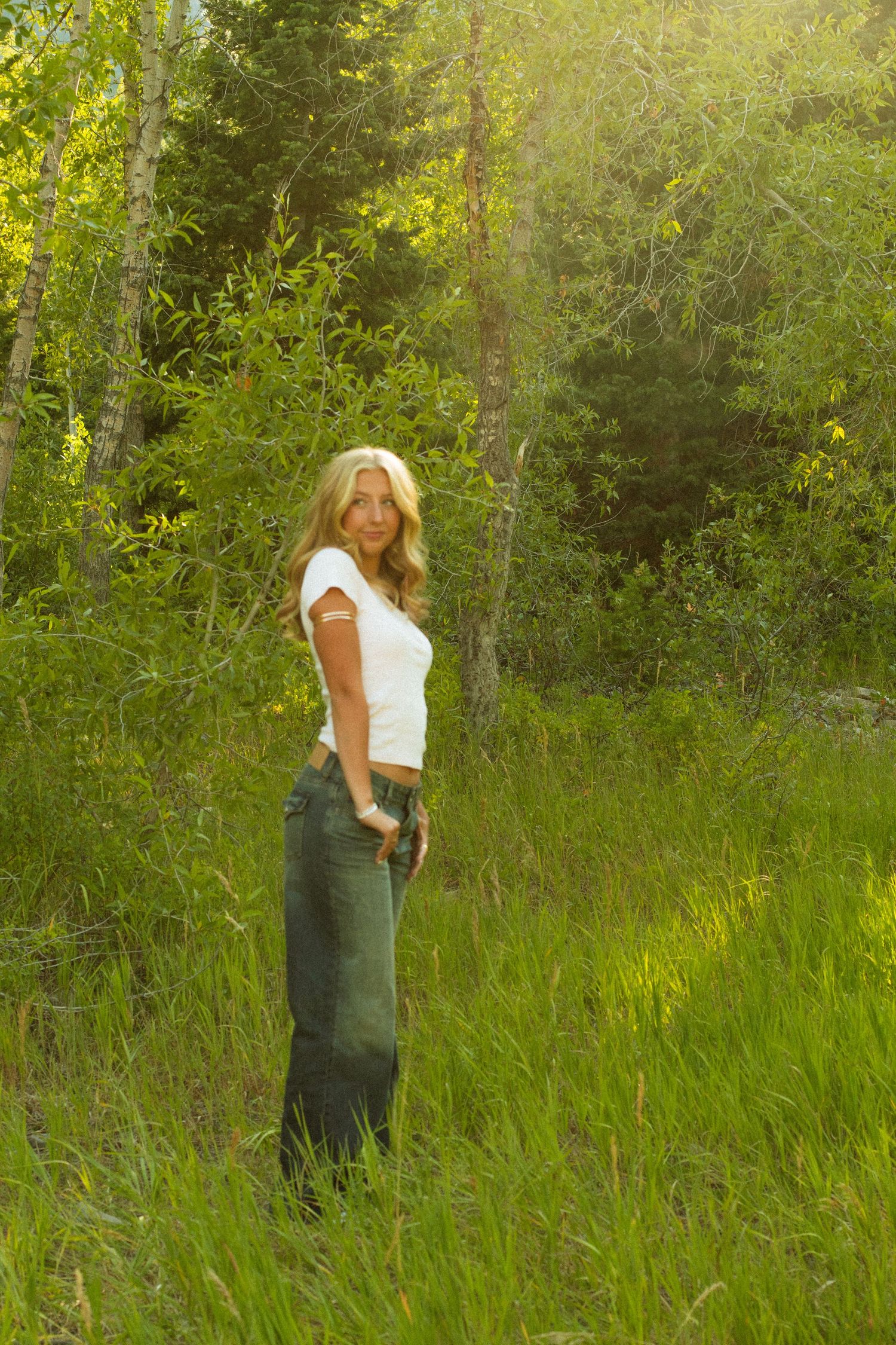 Summer portrait session in a sun-drenched field with natural greenery.