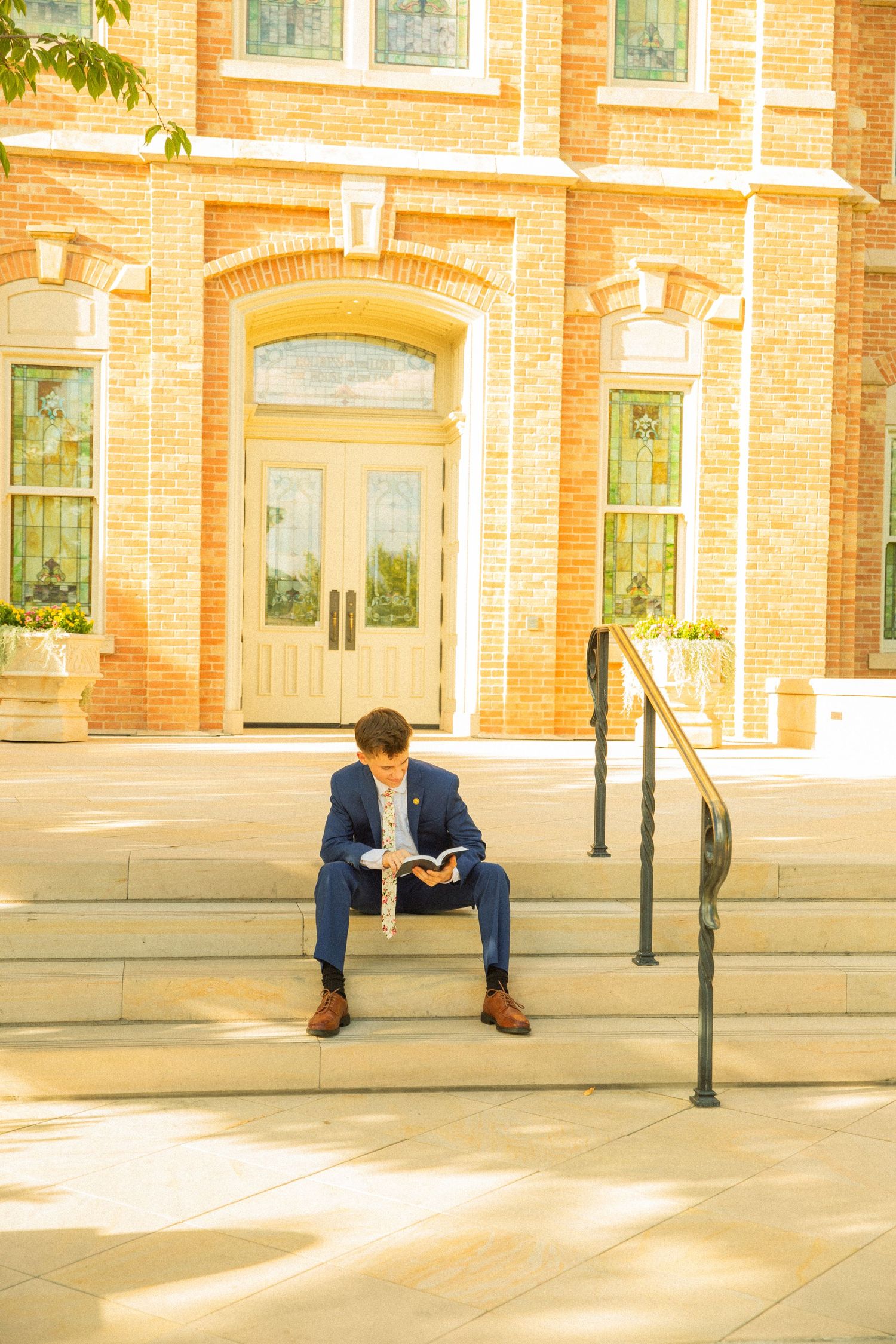 A person in a blue suit sits on concrete steps outside a brick building, shown in a sequence of four similar photos.