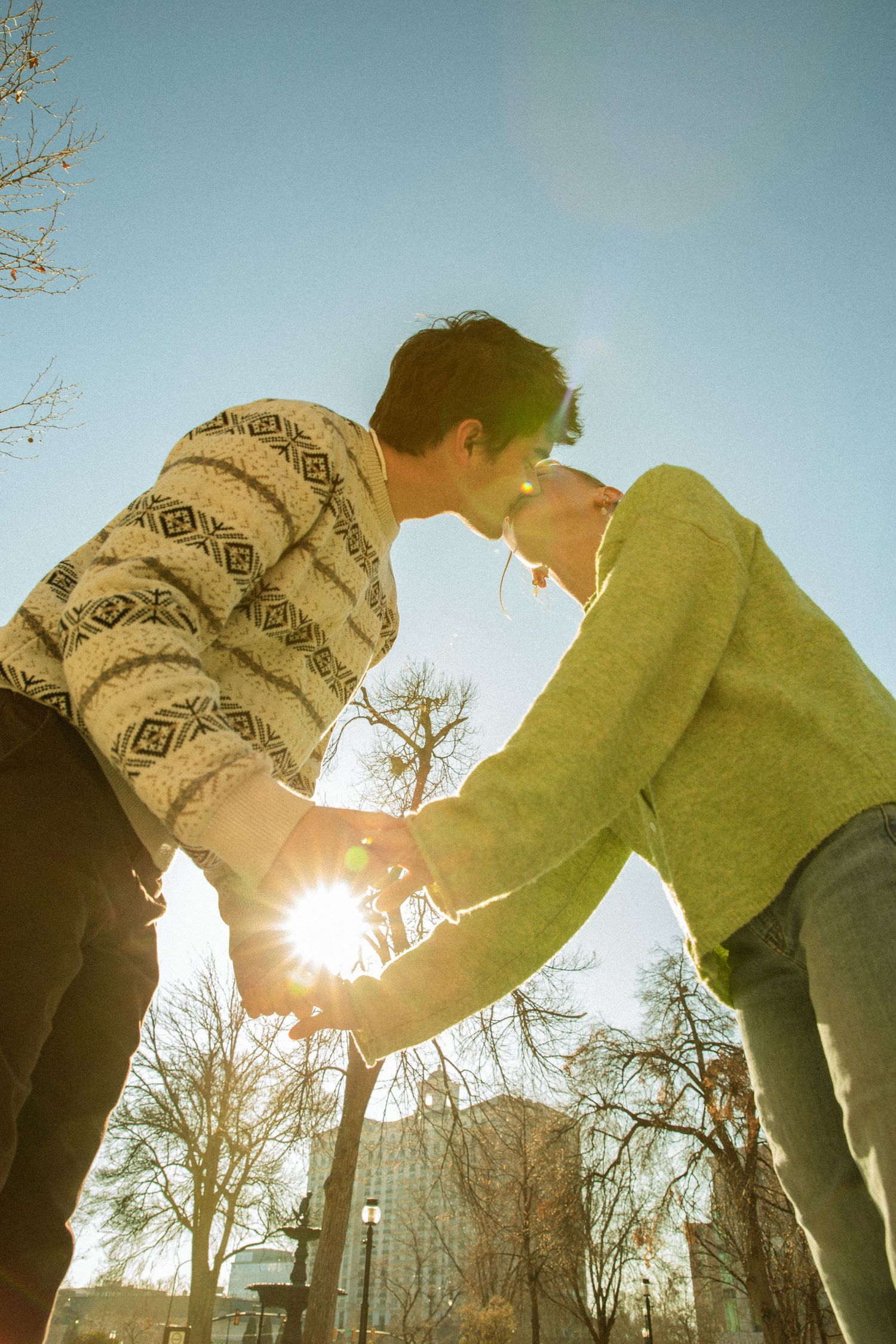 Person in green sweater and knit hat bends forward against bright sunlight in winter landscape.