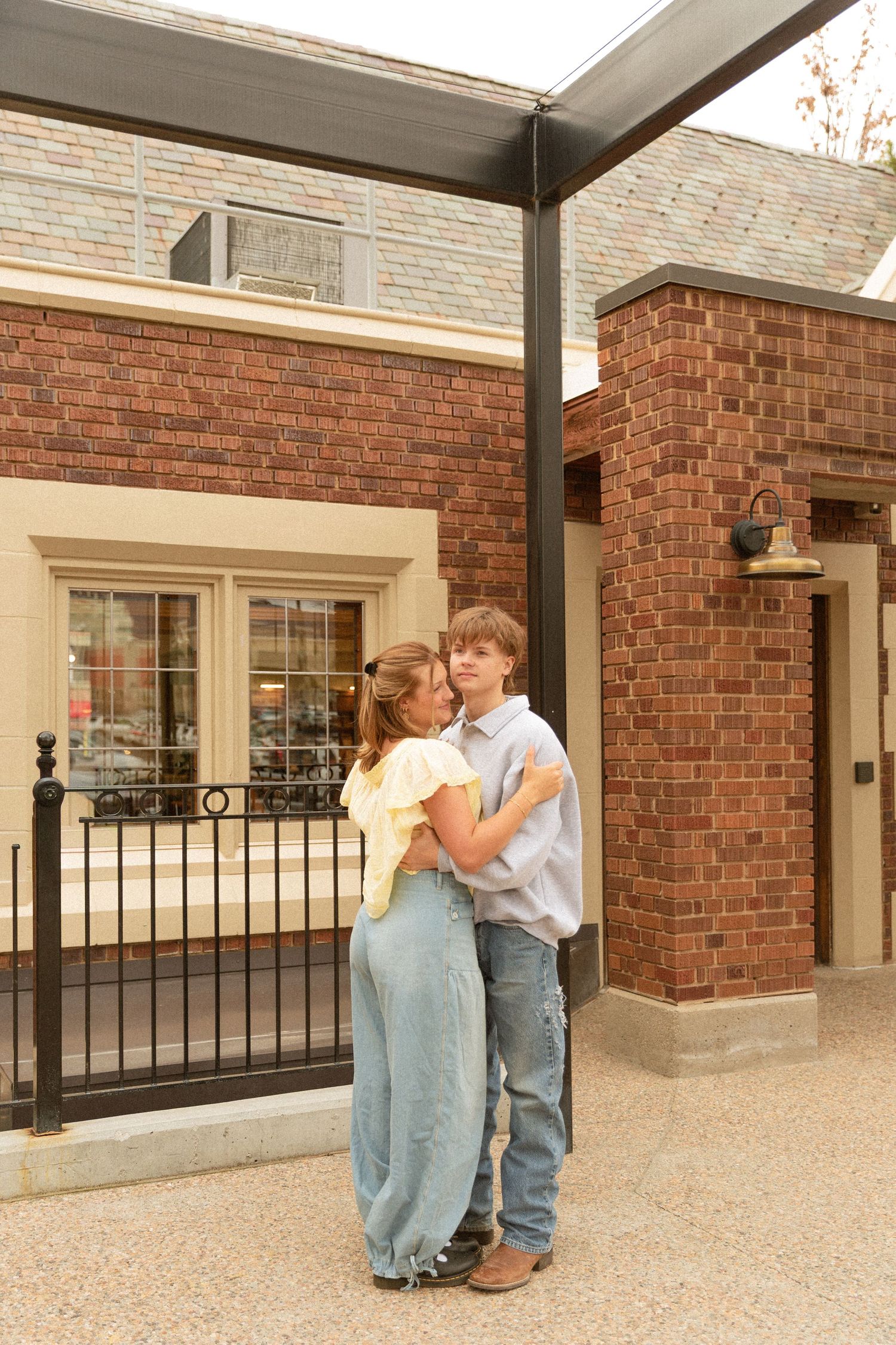 A couple embraces in a romantic moment on a covered patio with brick walls and stone flooring.