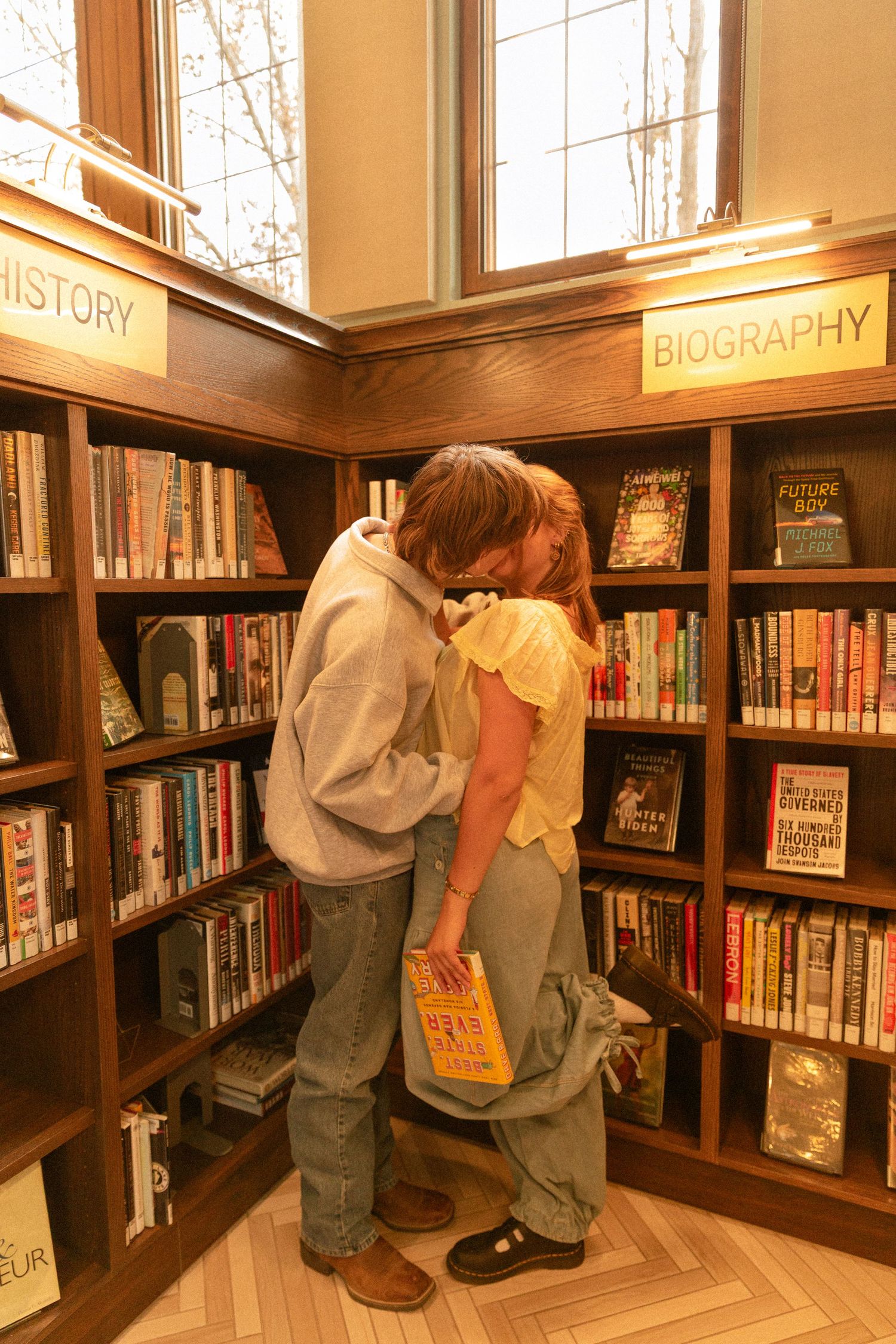 A series of photos showing someone searching through library bookshelves in the biography and history sections.